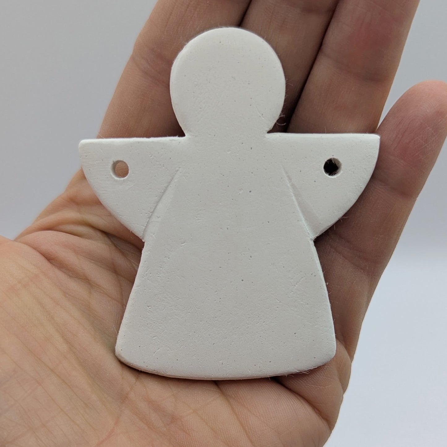 White clay angel ornament, held in a hand
