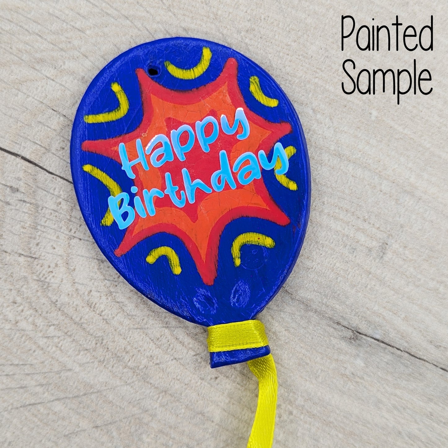 painted balloon clay decoration, painted in blue, red and yellow with holographic vinyl 'happy birthday' wording on
