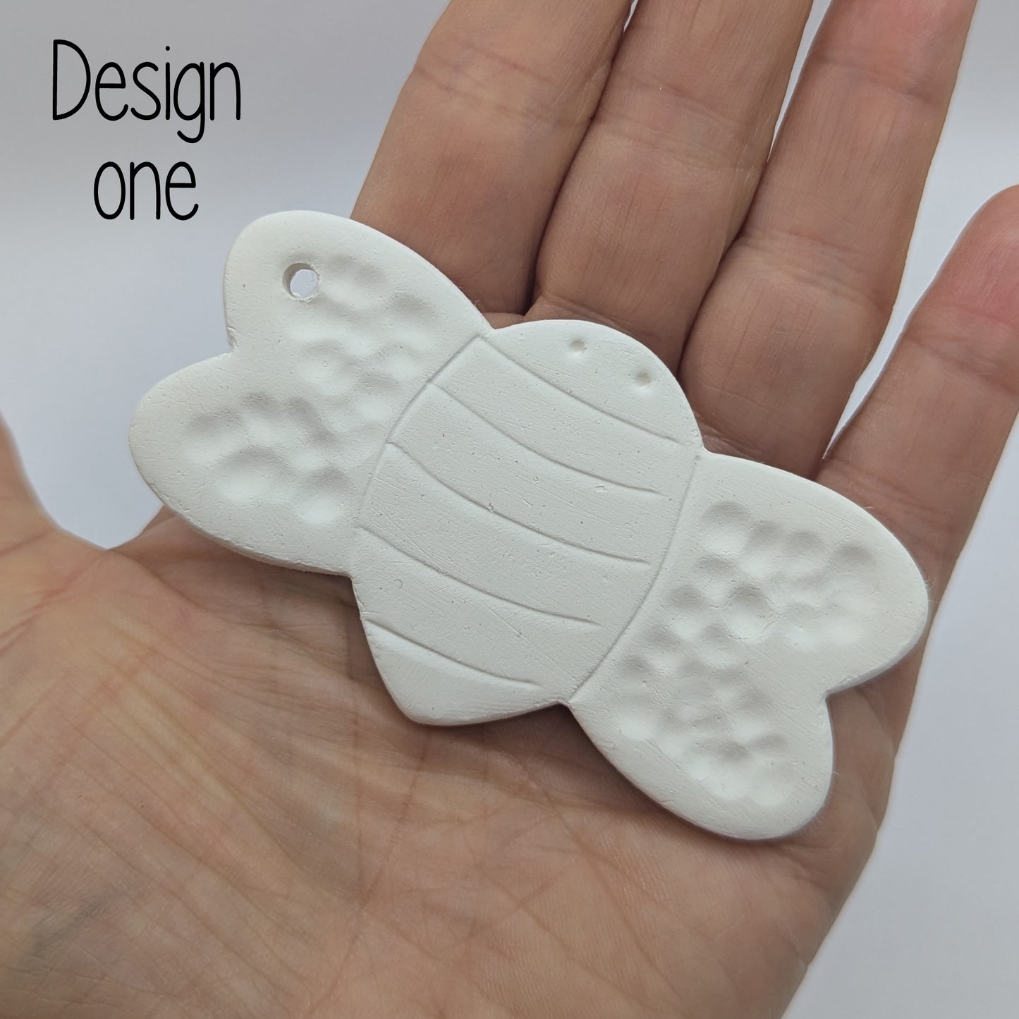 clay bee decoration shown in ladies hand for scale
