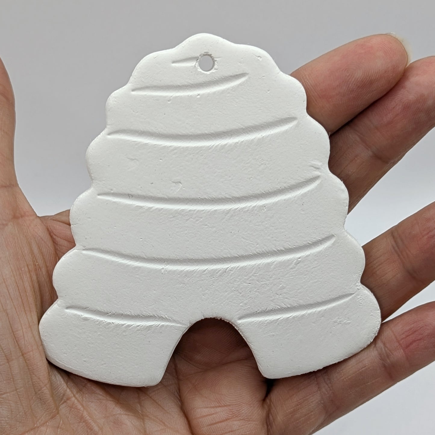beehive air dried clay decoration shown in a palm of hand
