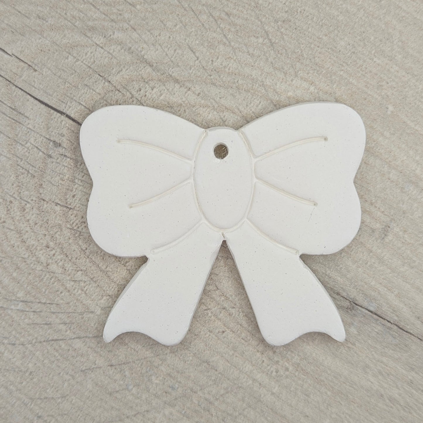 White bow-shaped clay decoration on a wooden surface