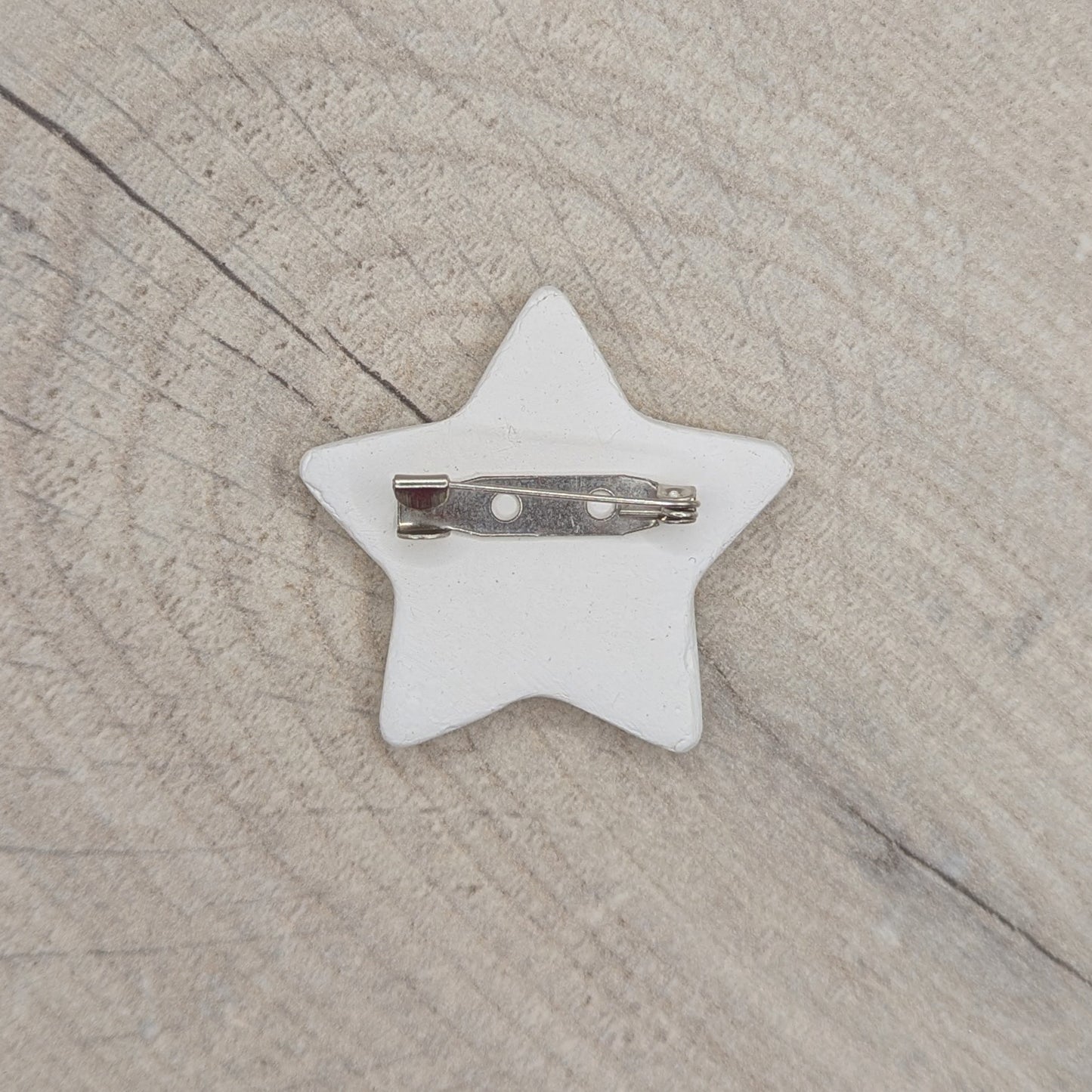 Star-shaped clay decoration with brooch on back