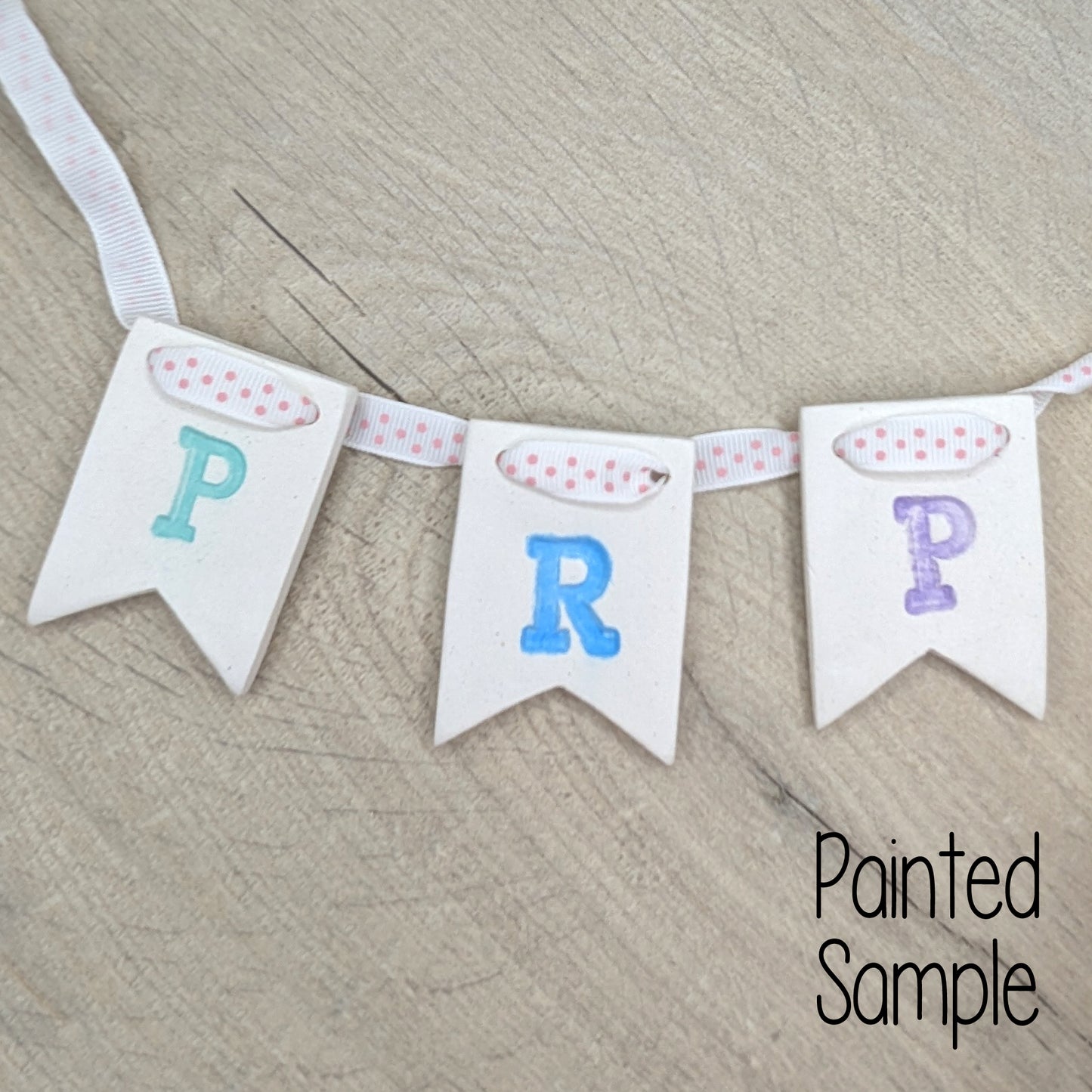 clay bunting banner with 'P R P' letters stamped into the clay to represent Penny's Rainbow