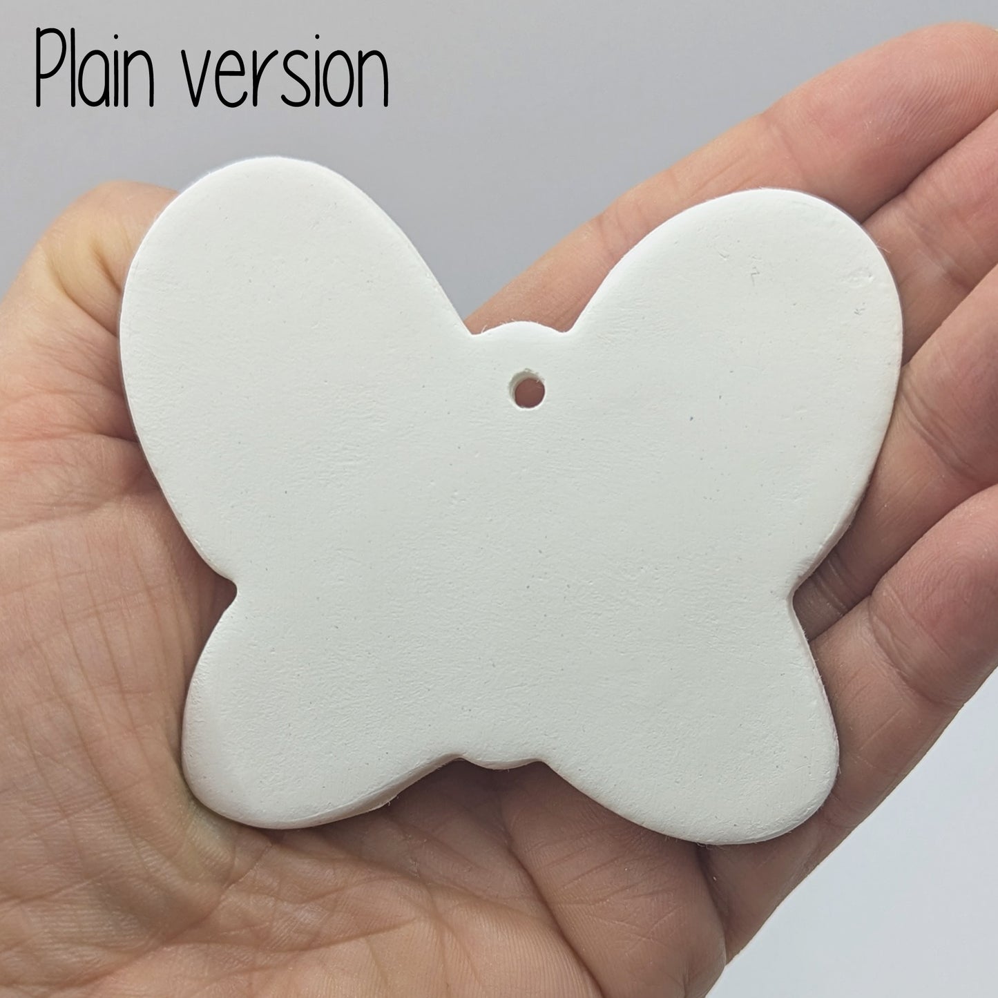 small plain air dried clay butterfly decoration, in a ladies hand to show scale