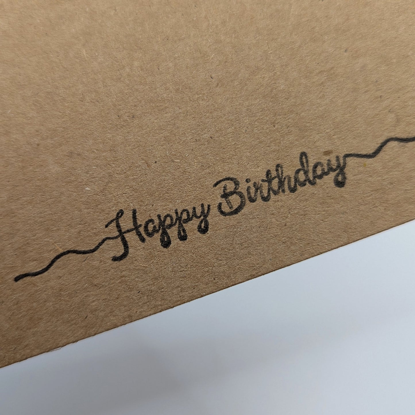 happy birthday stamped in black ink onto a kraft card