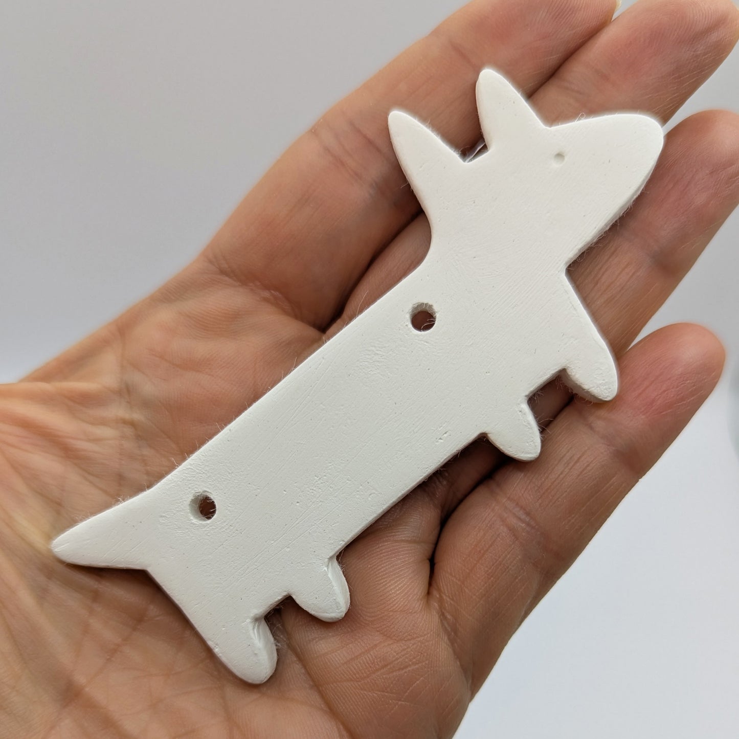 stylised Dachshund dog clay dog decoration being held in a hand to show size