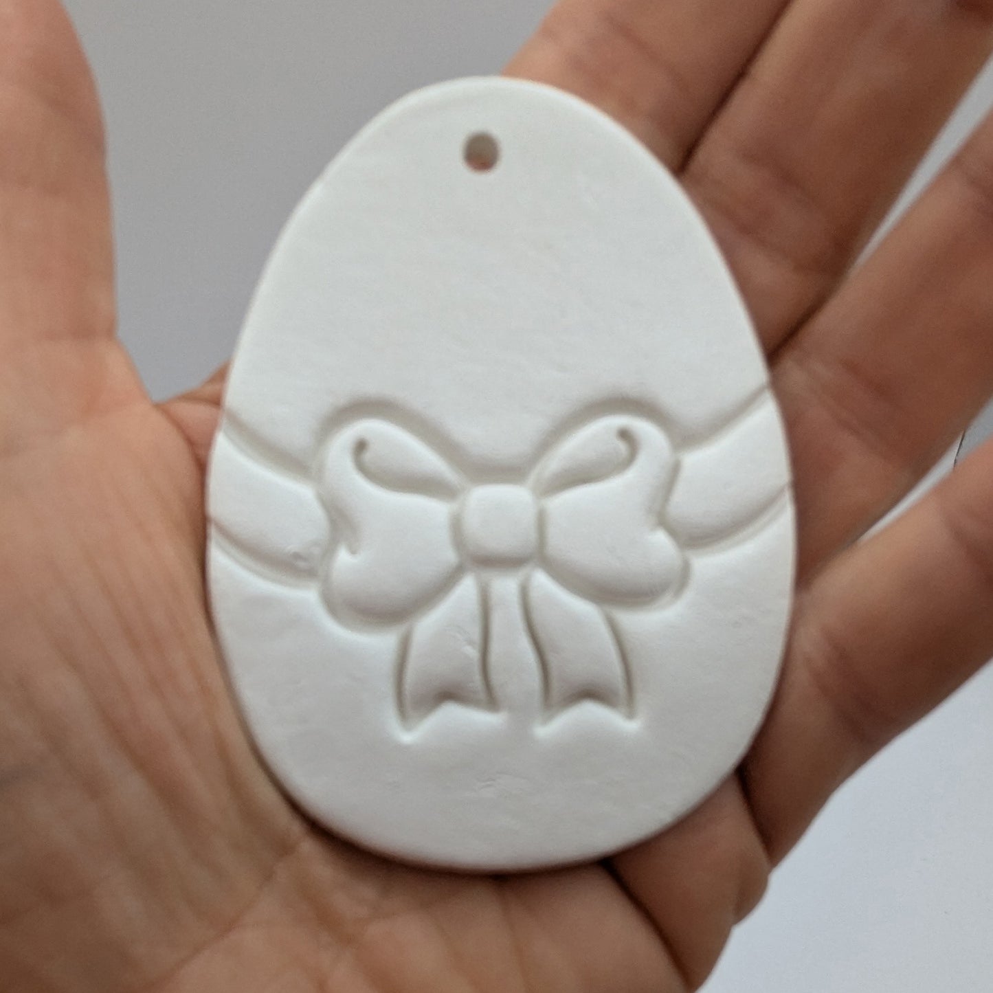 bow design easter egg clay decoration in palm of hand