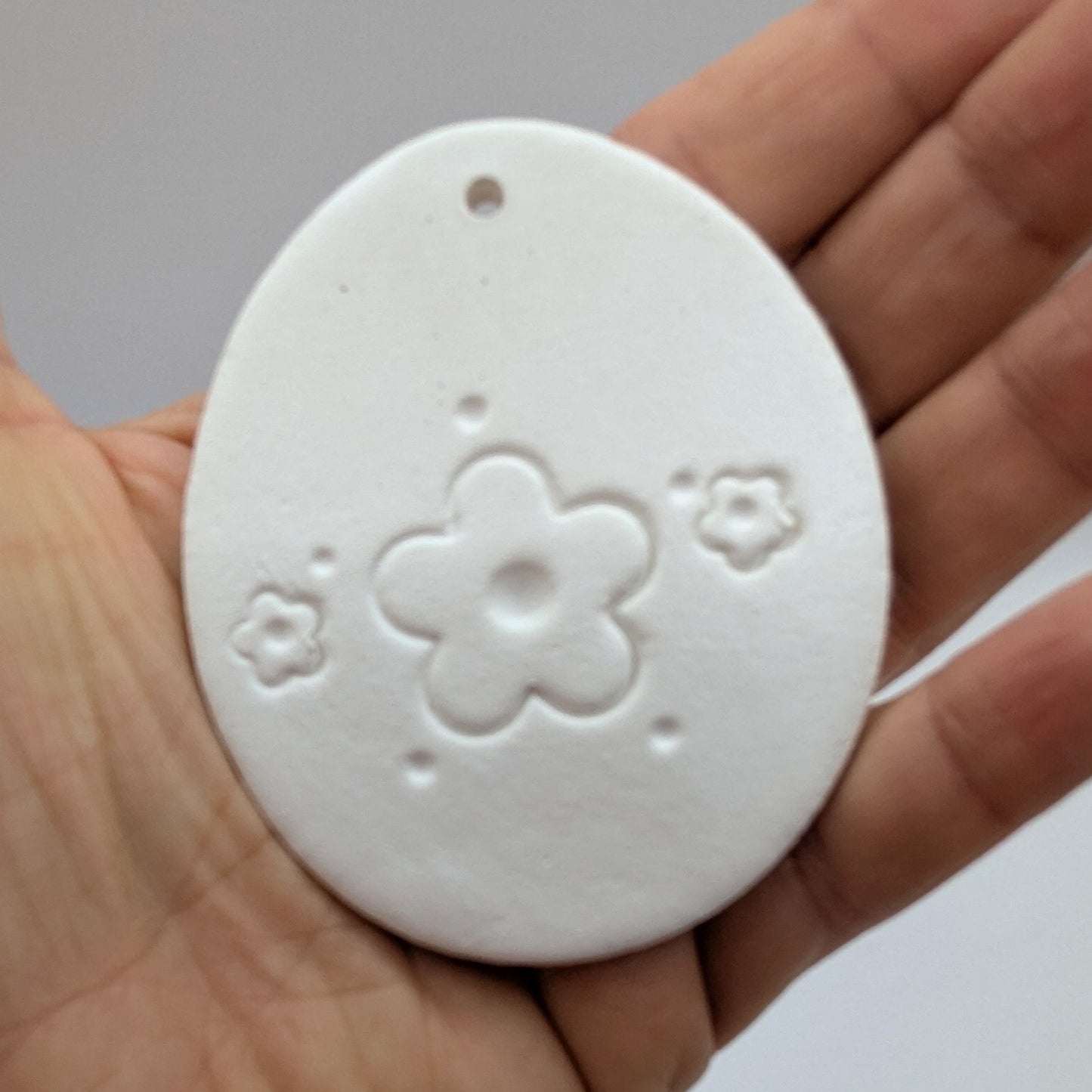 flower design easter egg clay decoration held in palm of hand