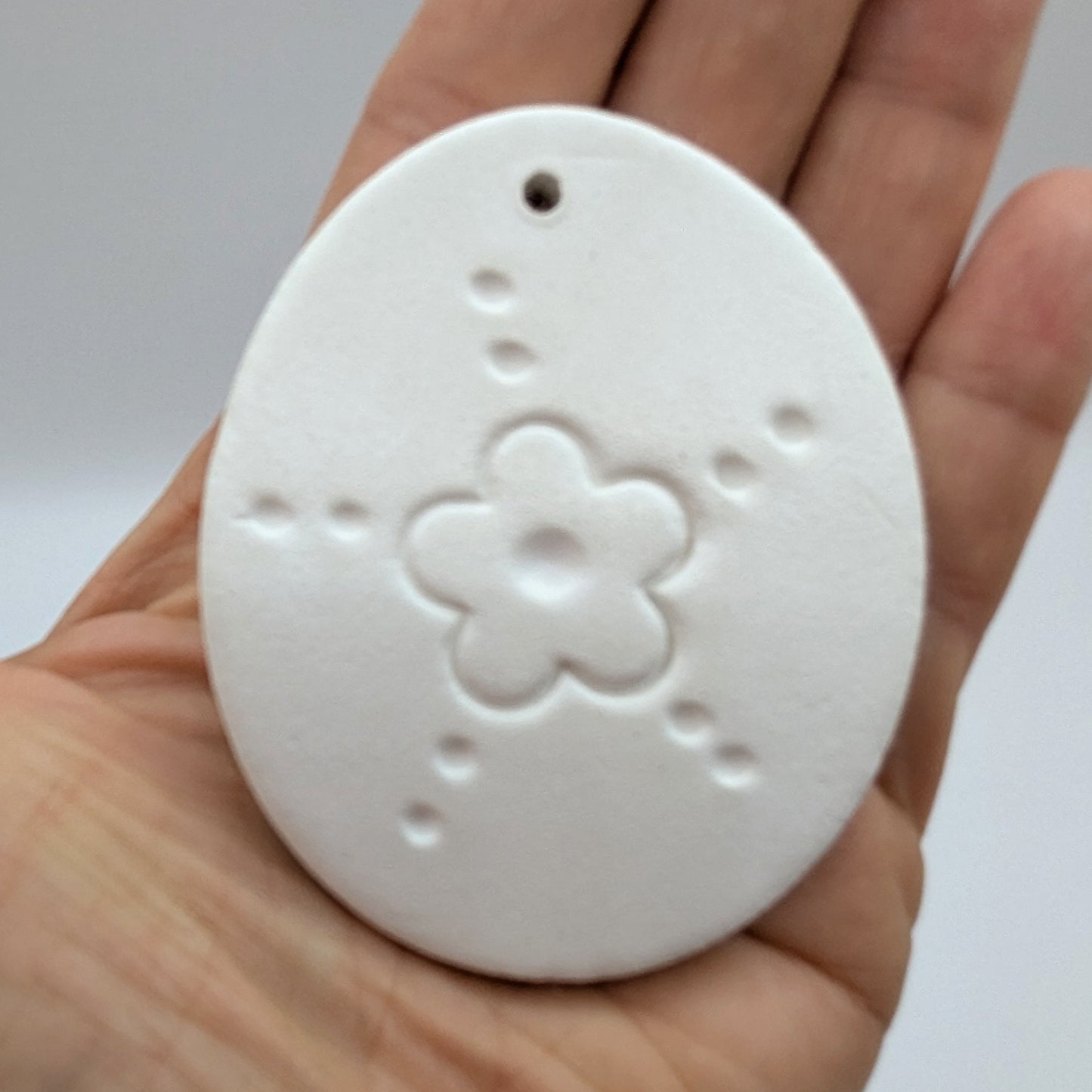 flower design easter egg clay decoration held in palm of hand