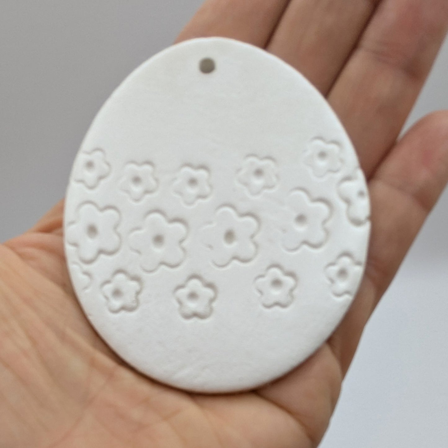 flower design easter egg clay decoration held in palm of hand