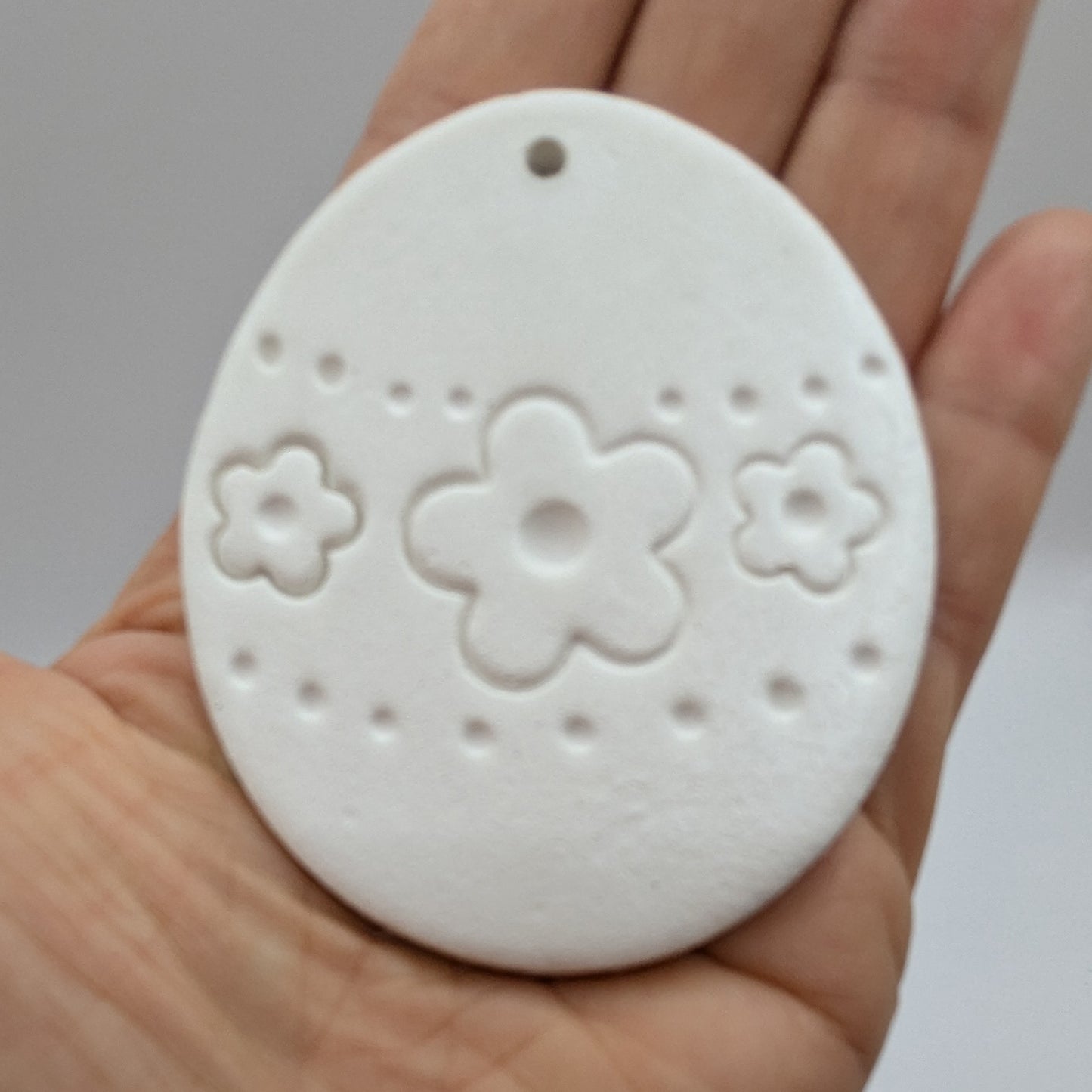 flower design easter egg clay decoration held in palm of hand