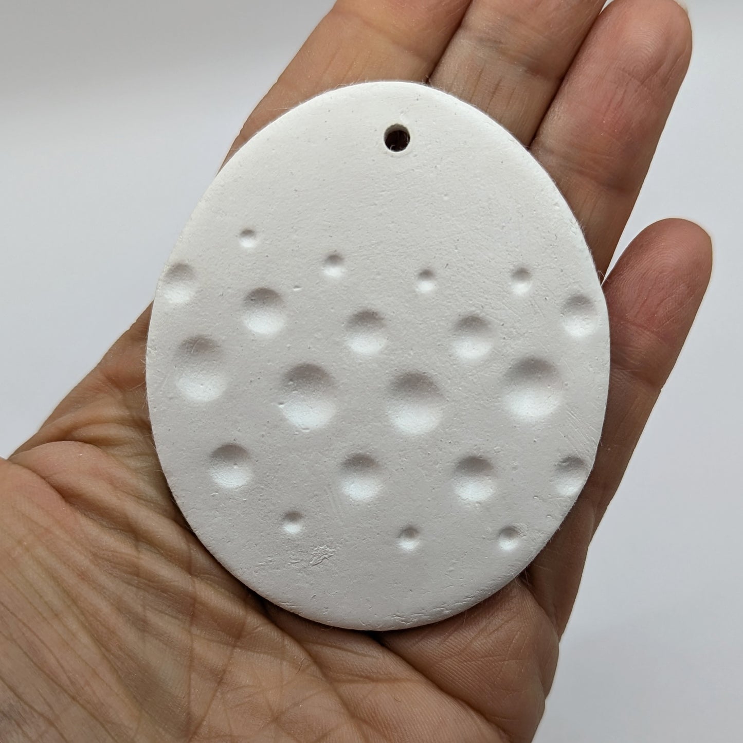 spotted easter egg clay decoration held in palm of hand
