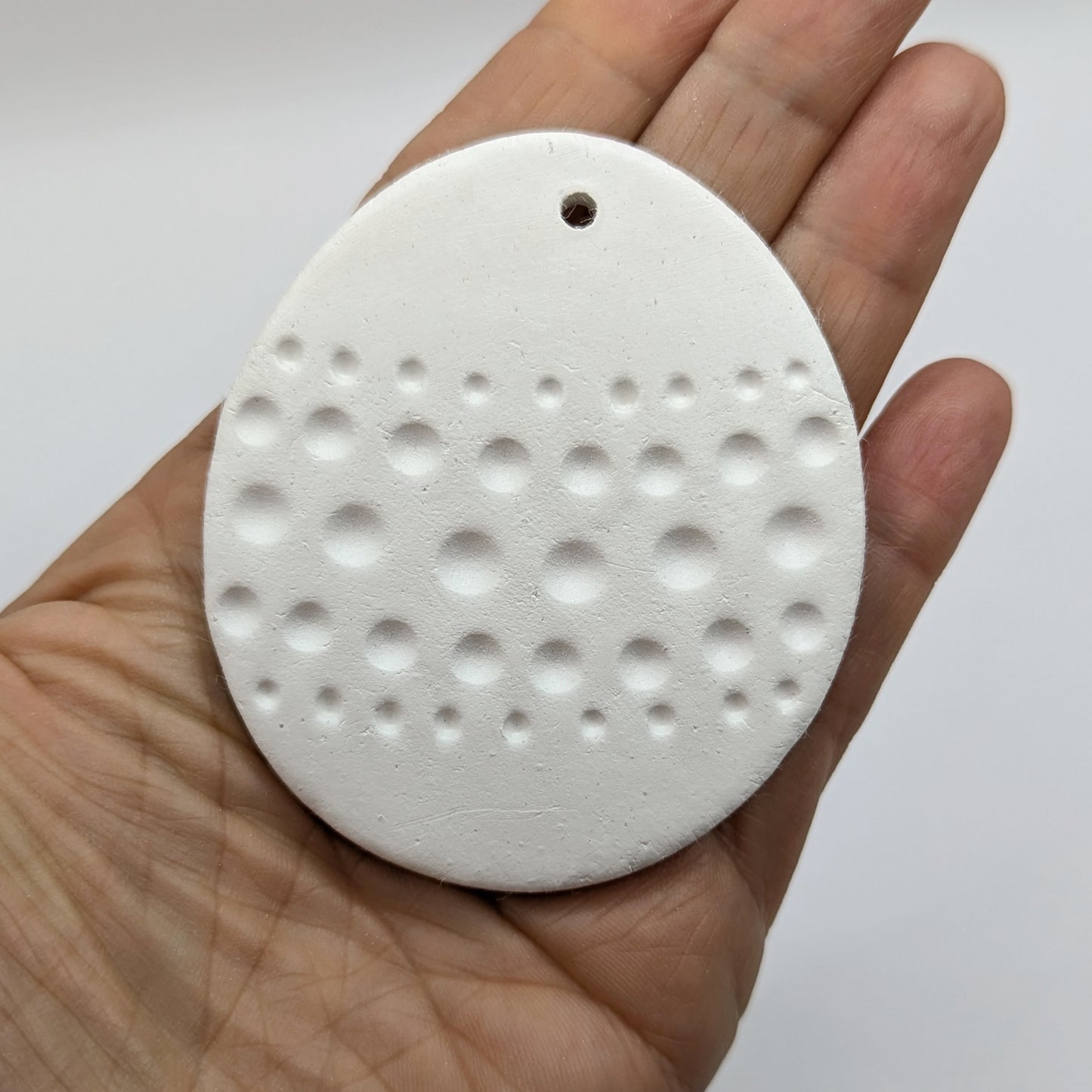 spotted easter egg clay decoration held in palm of hand
