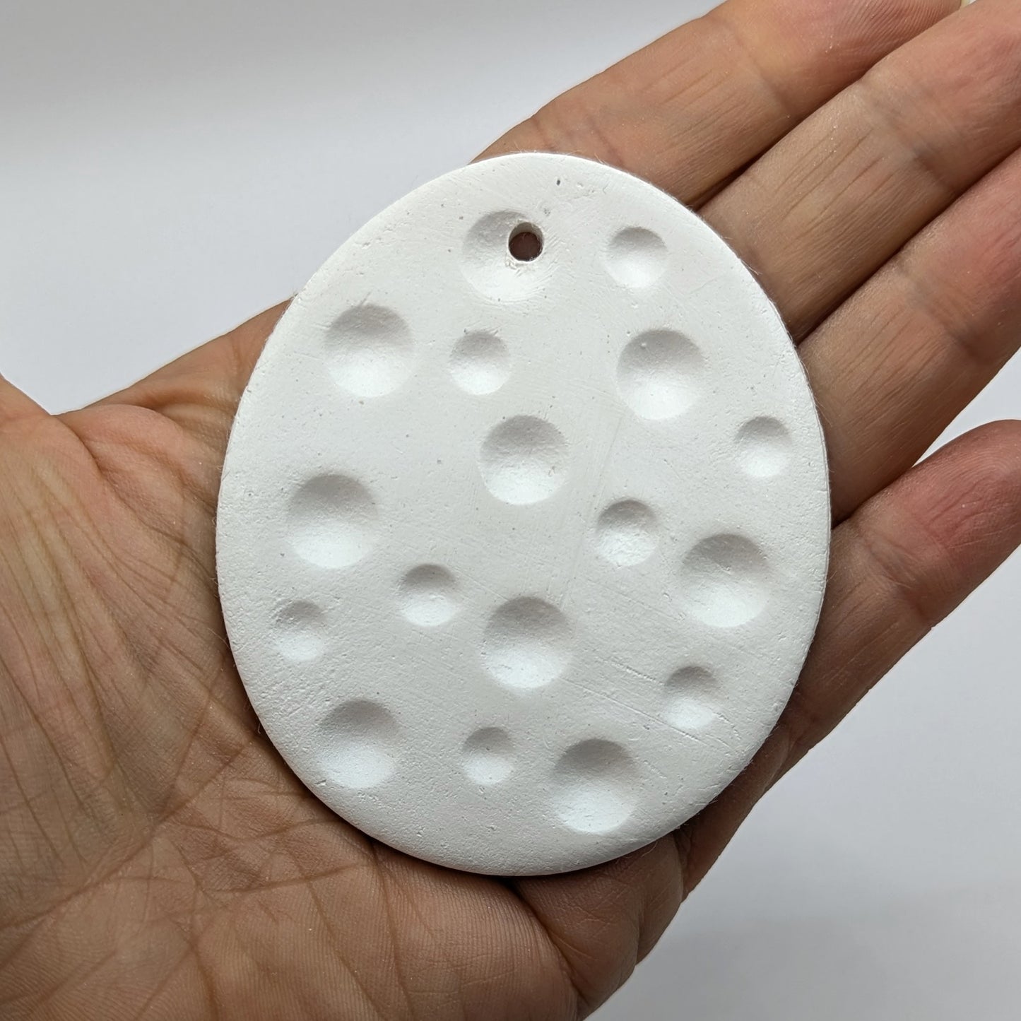 spotted easter egg clay decoration held in palm of hand