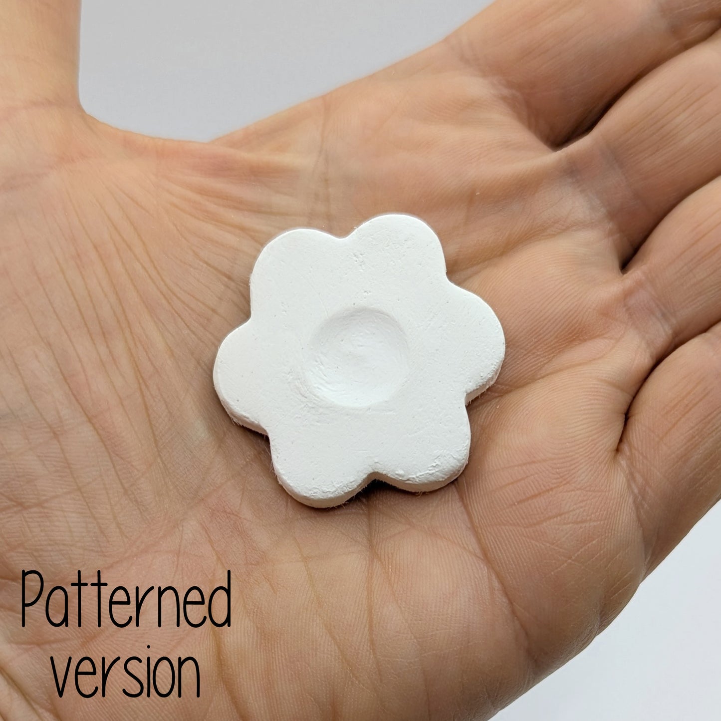 small flower shaped clay decoration shown in palm of hand