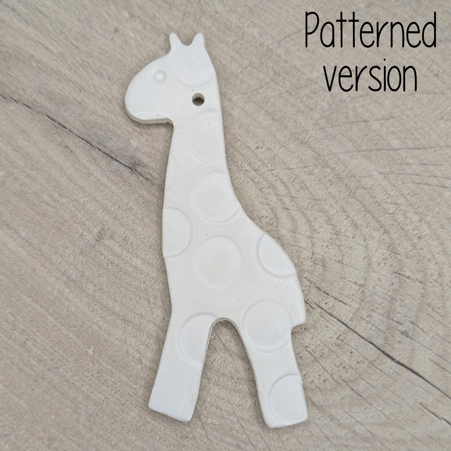 White giraffe shaped clay decoration on a wooden surface, patterned / spotted version