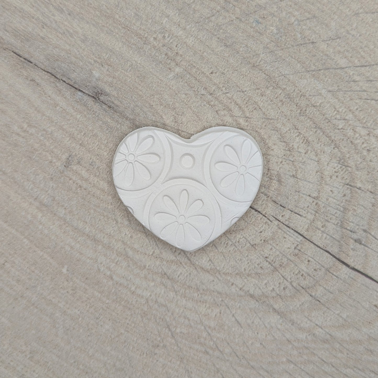 small patterned heart clay decoration displayed on wooden background
