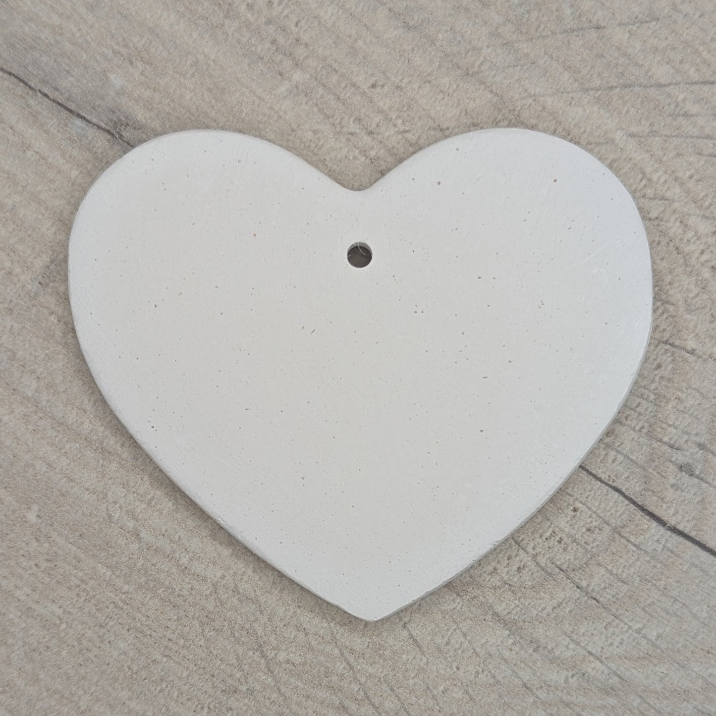 Heart shaped air dried clay decoration / tag / ornament on a wooden surface