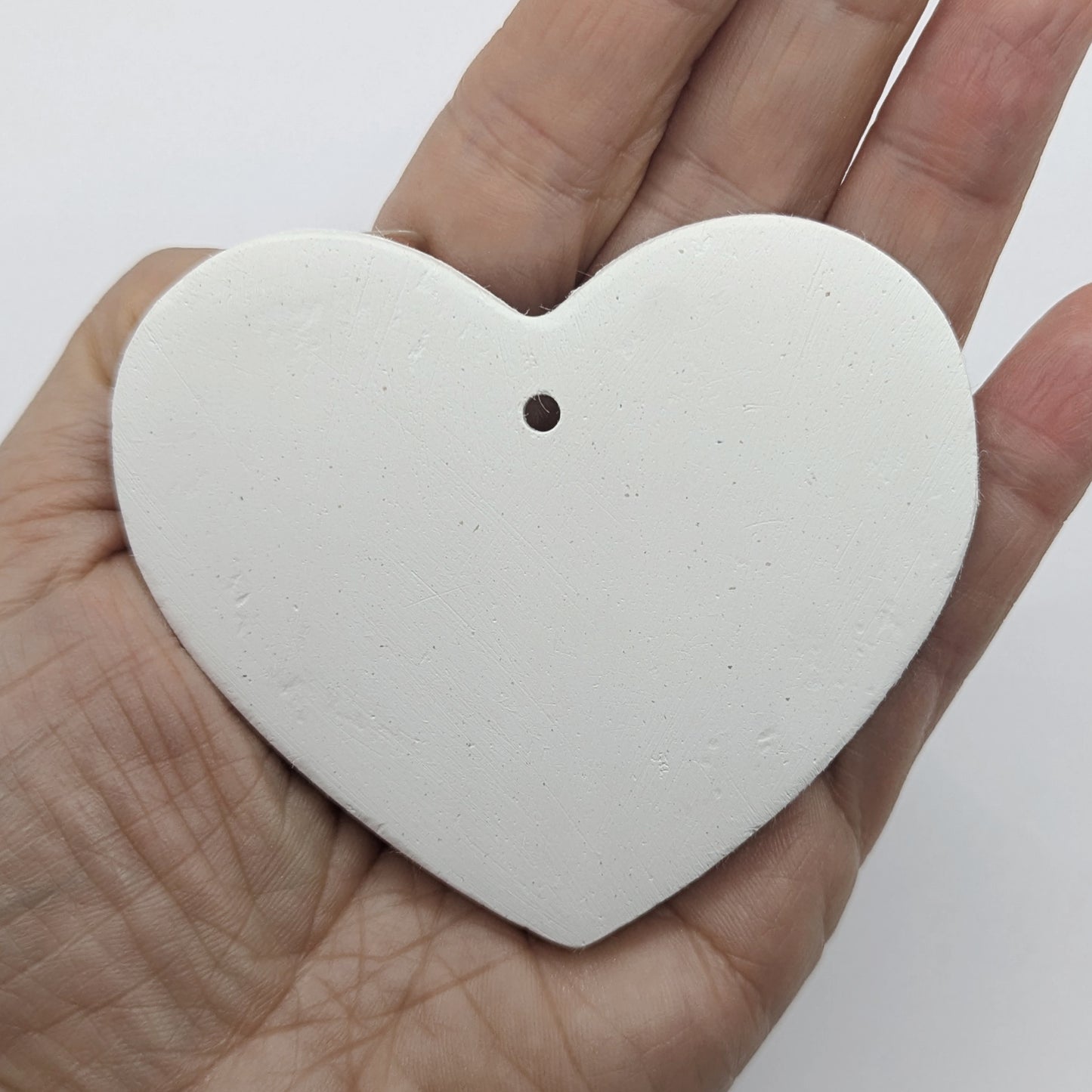 Heart shaped air dried clay decoration / tag in some ones hand to show size