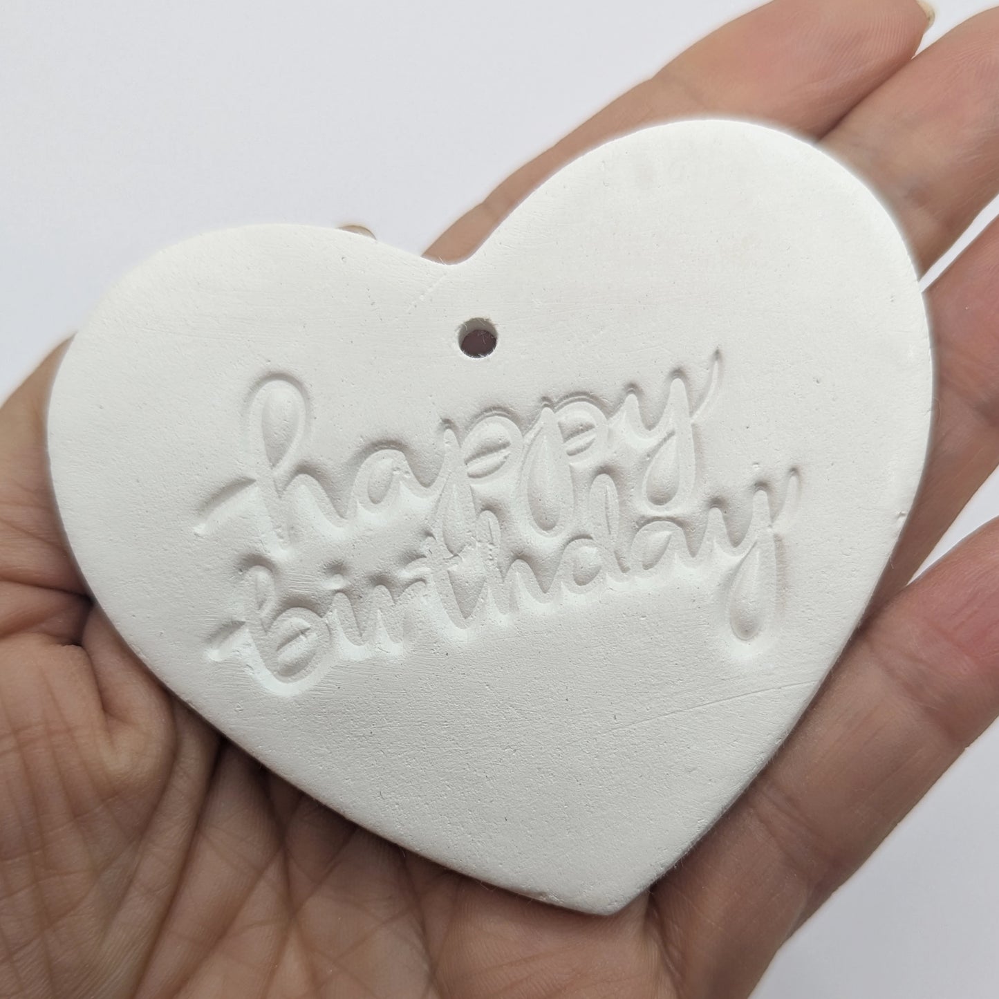 Heart shaped air dried clay decoration / tag with 'happy birthday' in lower case stamped into the clay