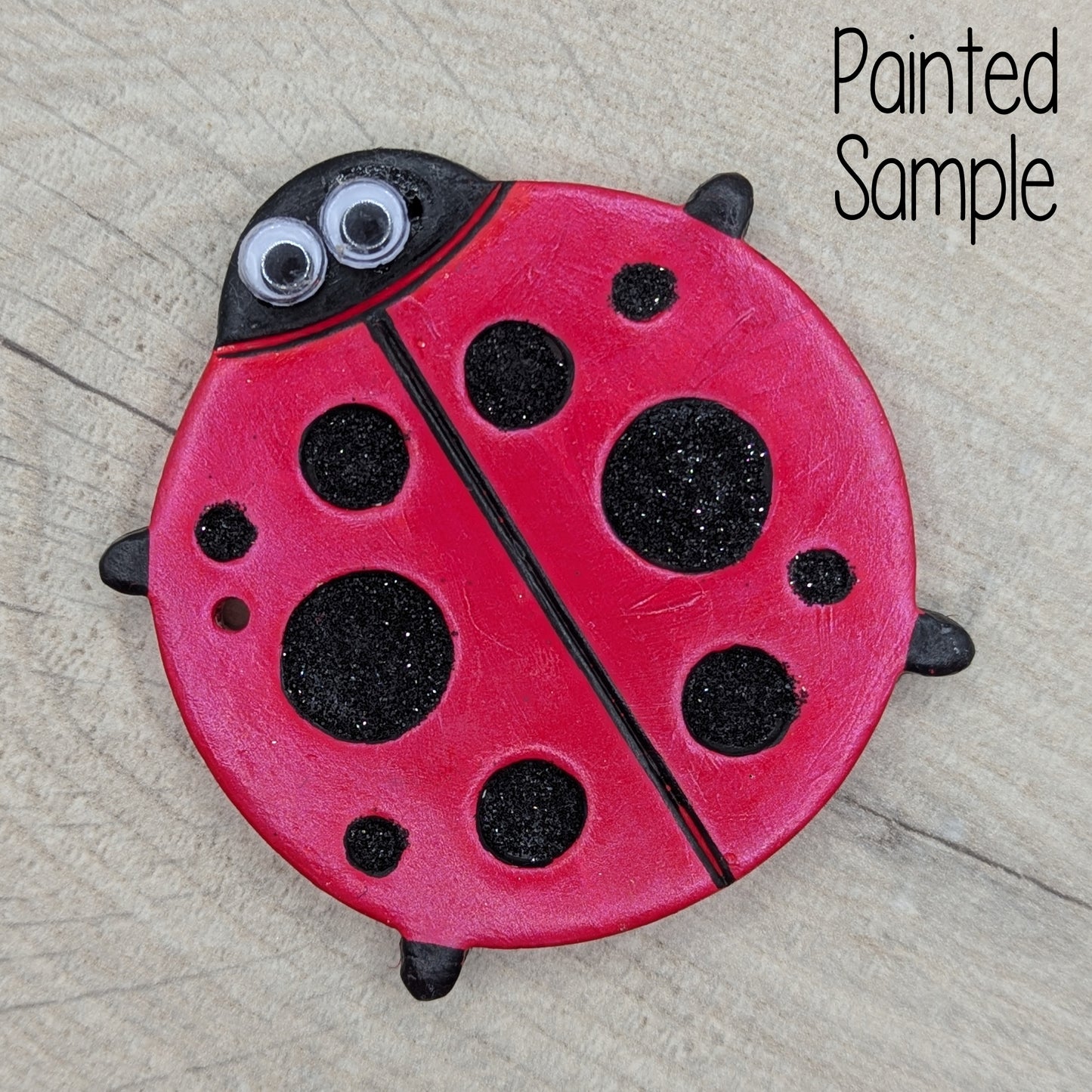 lady bug clay decoration painted in metallic red paint with large black glitter spots and a pair of boggle eyes