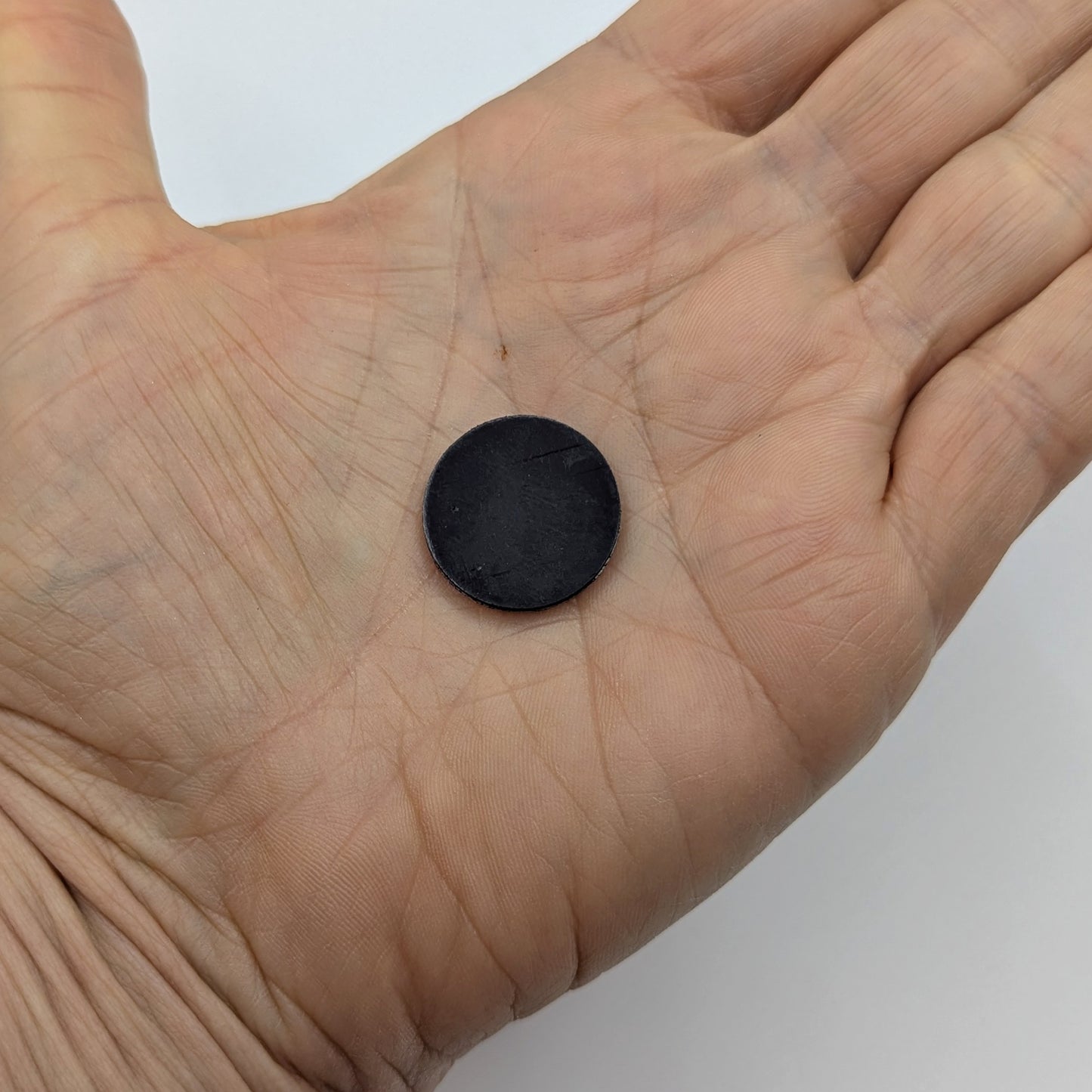 Black circular magnet on a person's palm