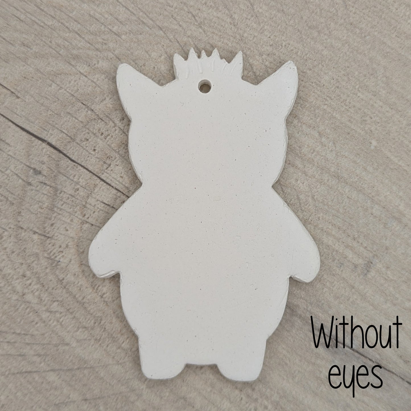 White silhouette of a funky monster with spikey hair, a pointy pair of ears on a wooden surface