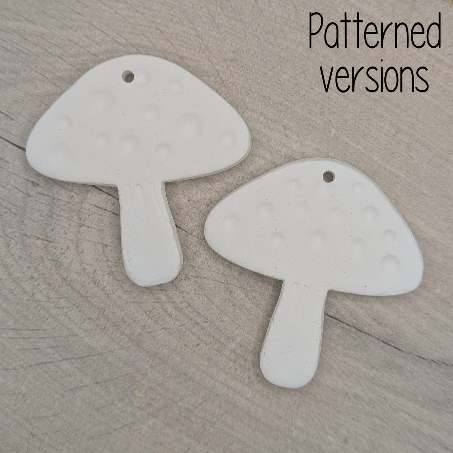 Two mushroom shaped clay decoration / tag on a wooden surface