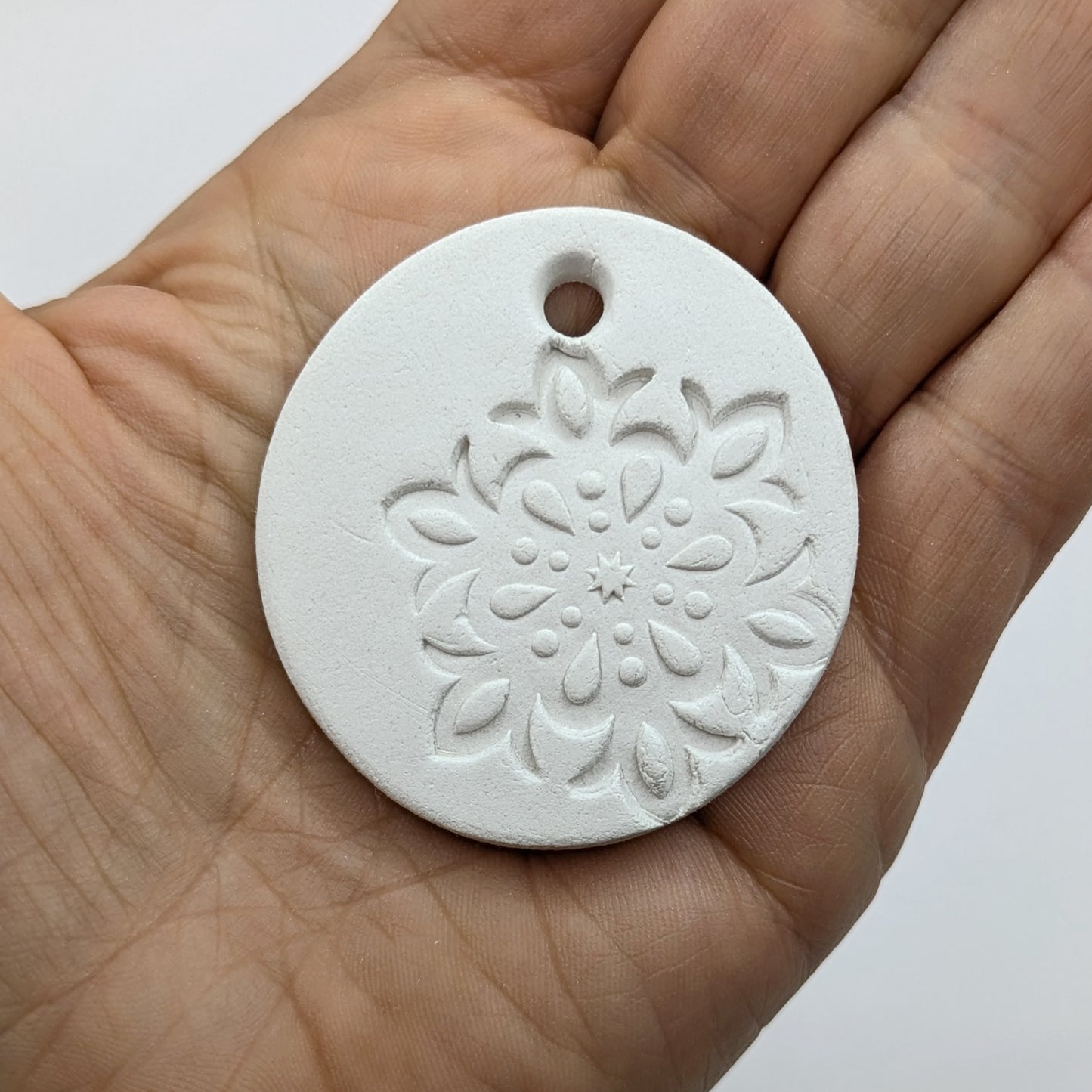 White clay snowflake tag held in a hand