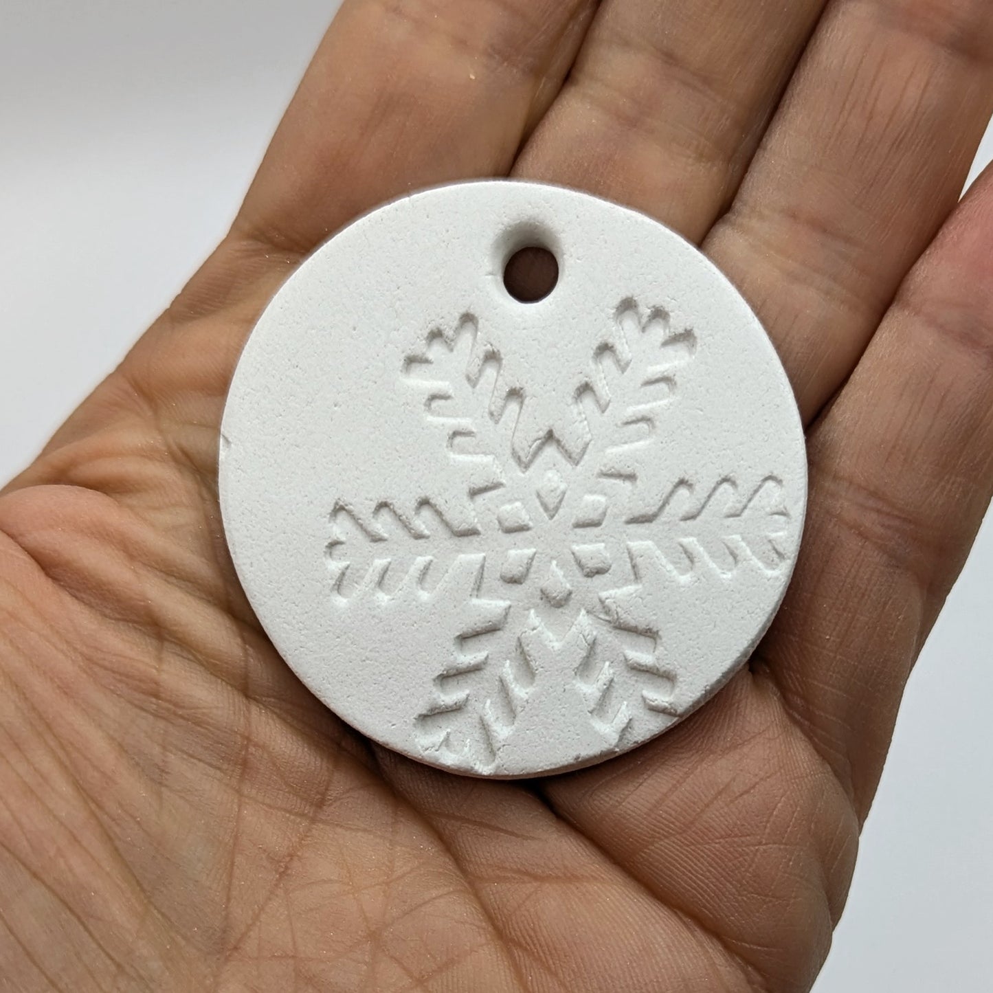 White clay snowflake tag held in a hand