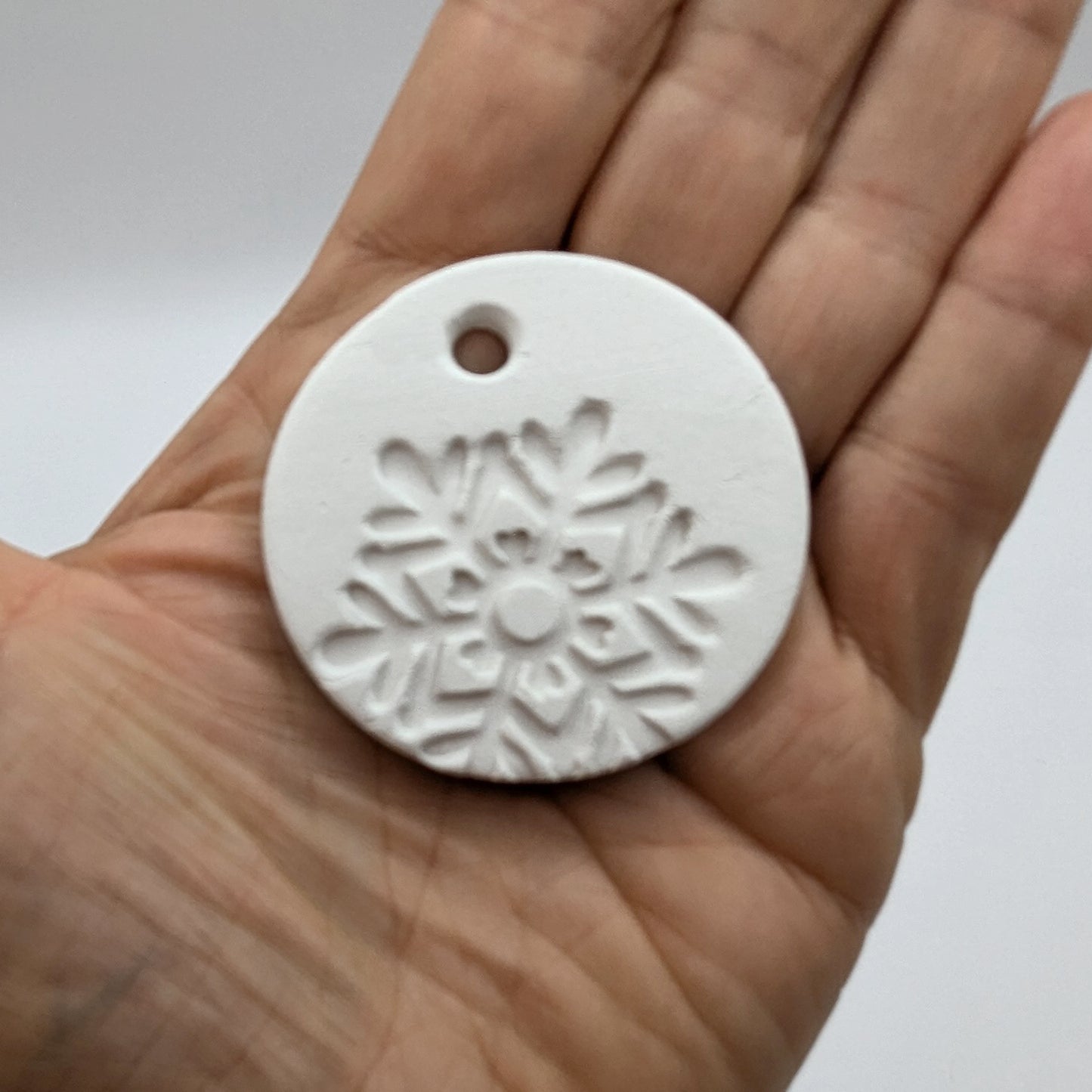 White clay snowflake tag held in a hand