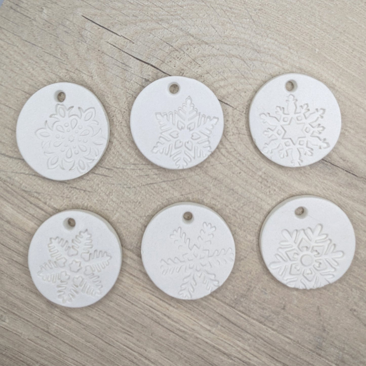 set of six white clay tags with snowflake patterns on - to show different designs