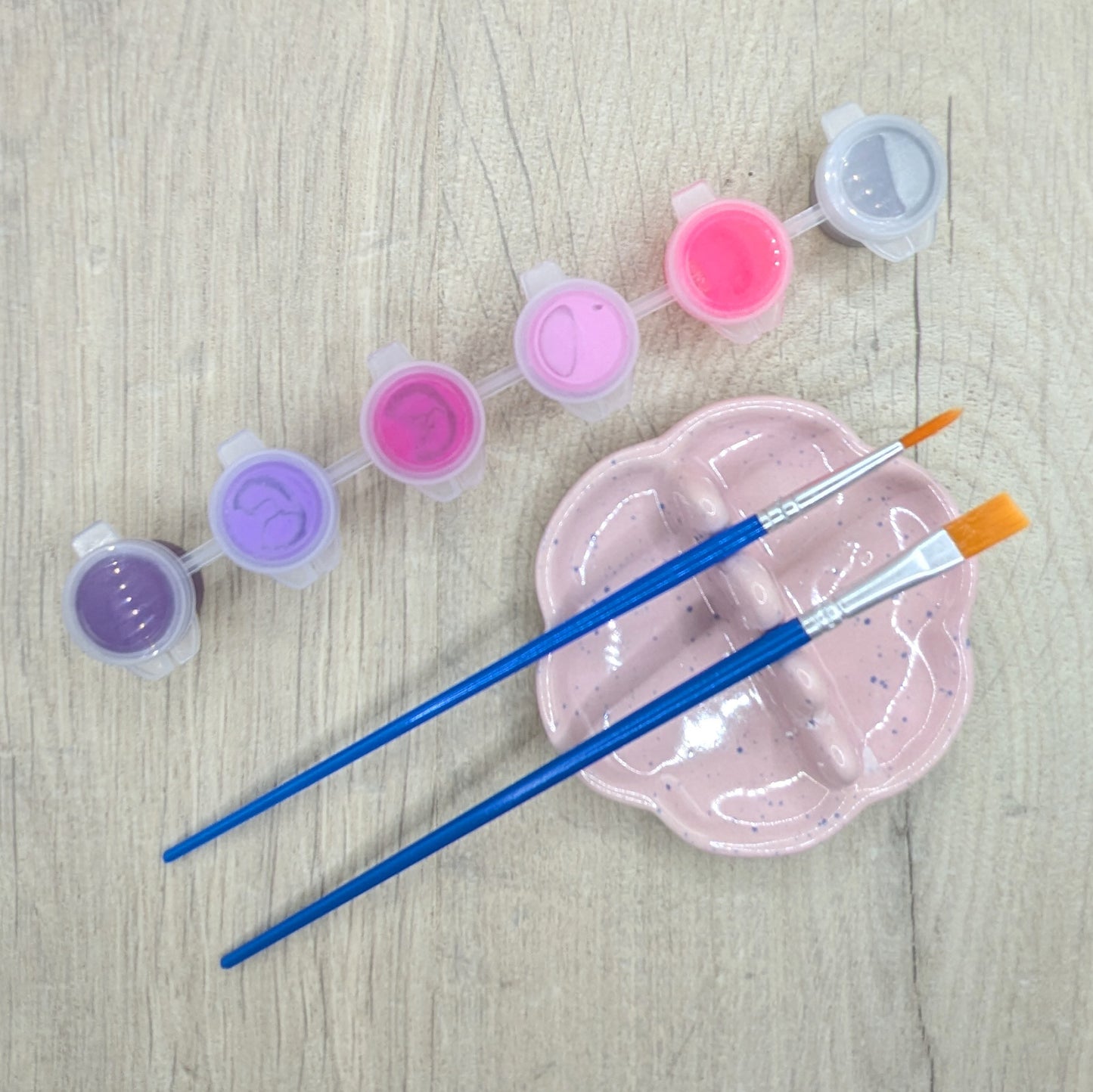 paint kit, showing 6 paints, purple, lilac, deep pink, light pink, bright pink and silver with 2 brushes