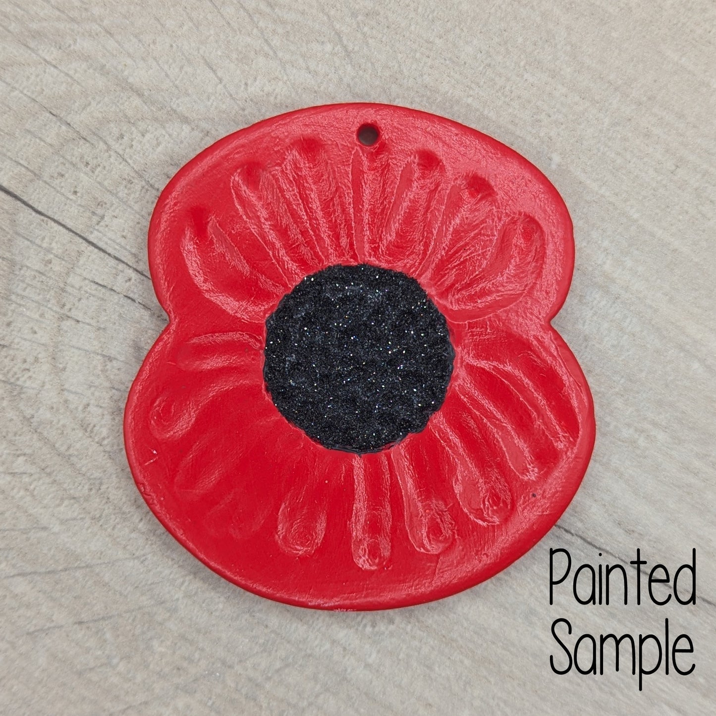 poppy decoration painted with red petals and a black glitter centre