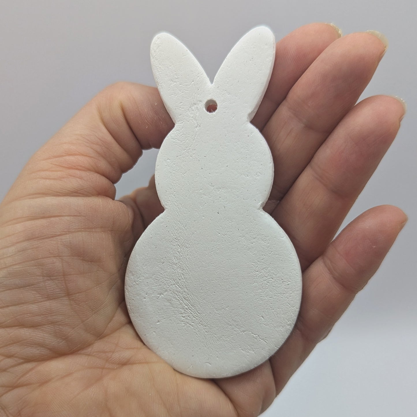 a clay decoration in the shape of a rabbit in some ones hand to show scale