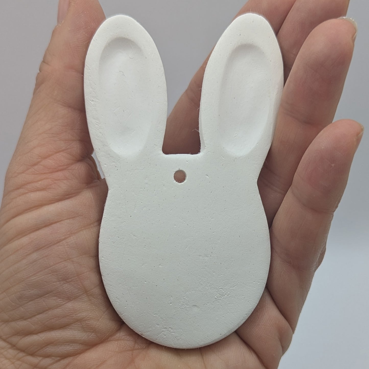 rabbit face air dried clay decoration in some ones hand to show scale