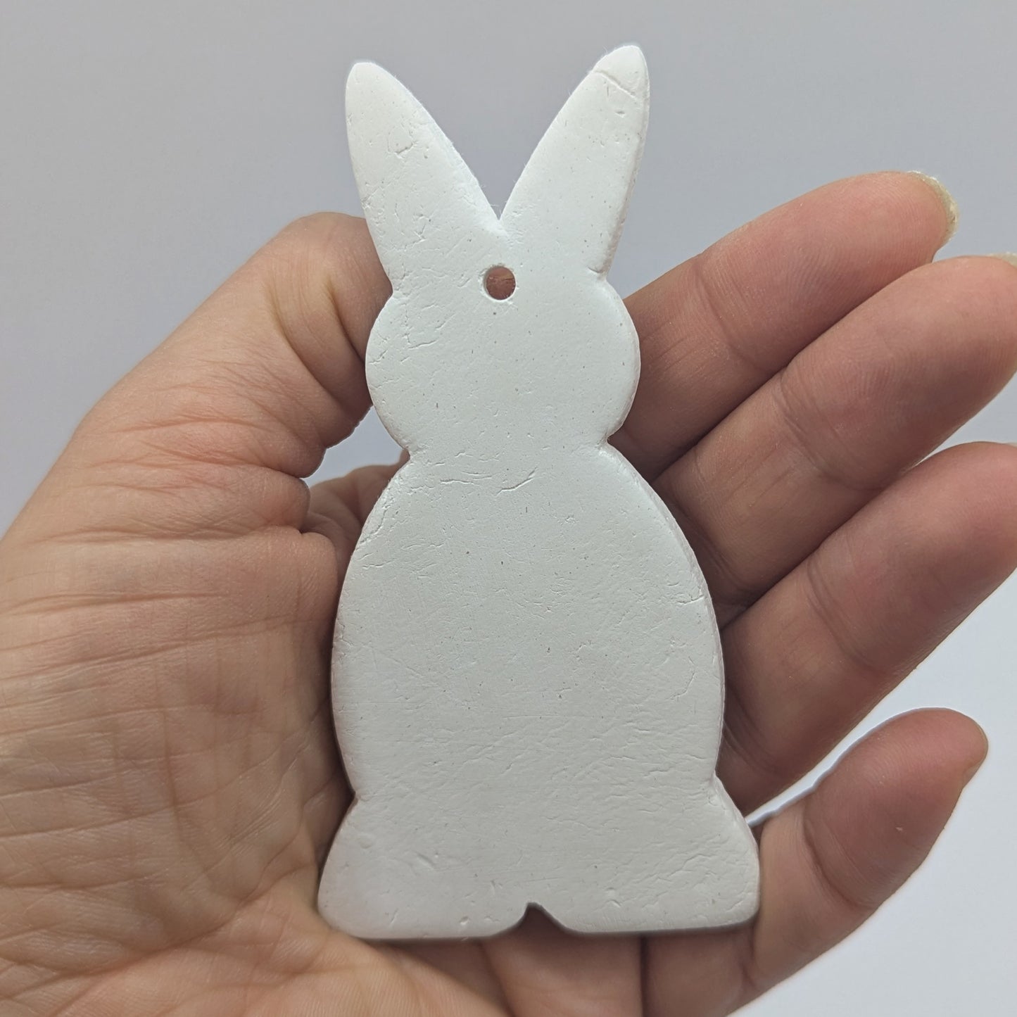 a clay decoration in the shape of a rabbit, in some ones hand to show scale