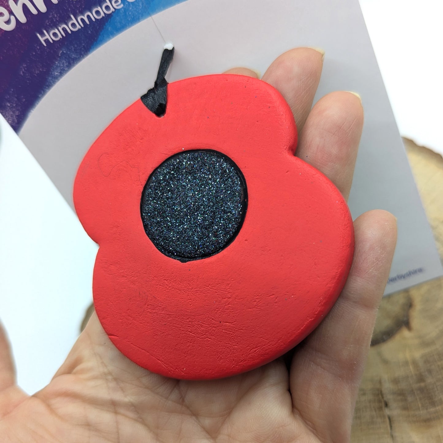 painted clay decoration in red and black with glitter centre being held to show size