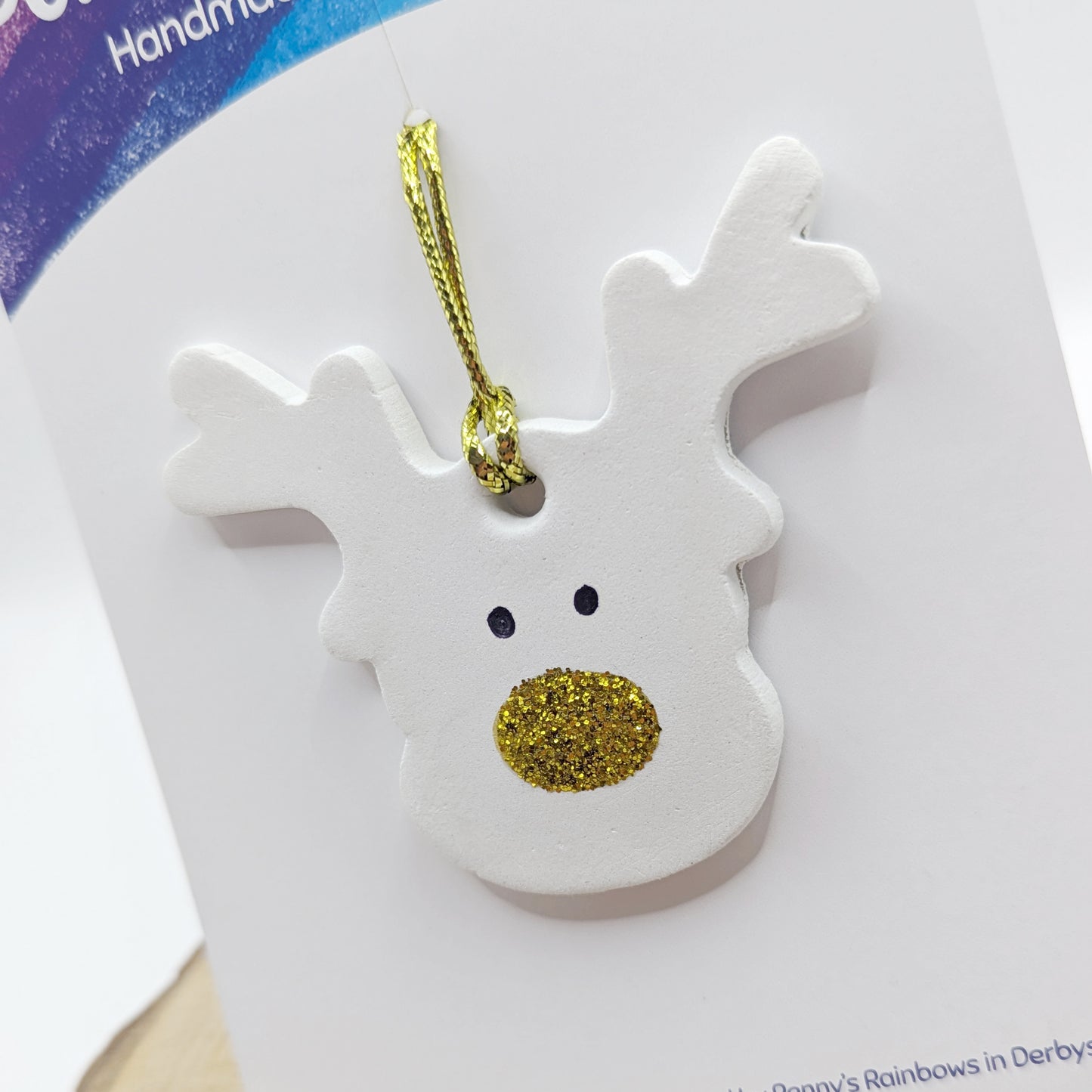 White clay reindeer ornament with gold glittery nose and antlers on a white card