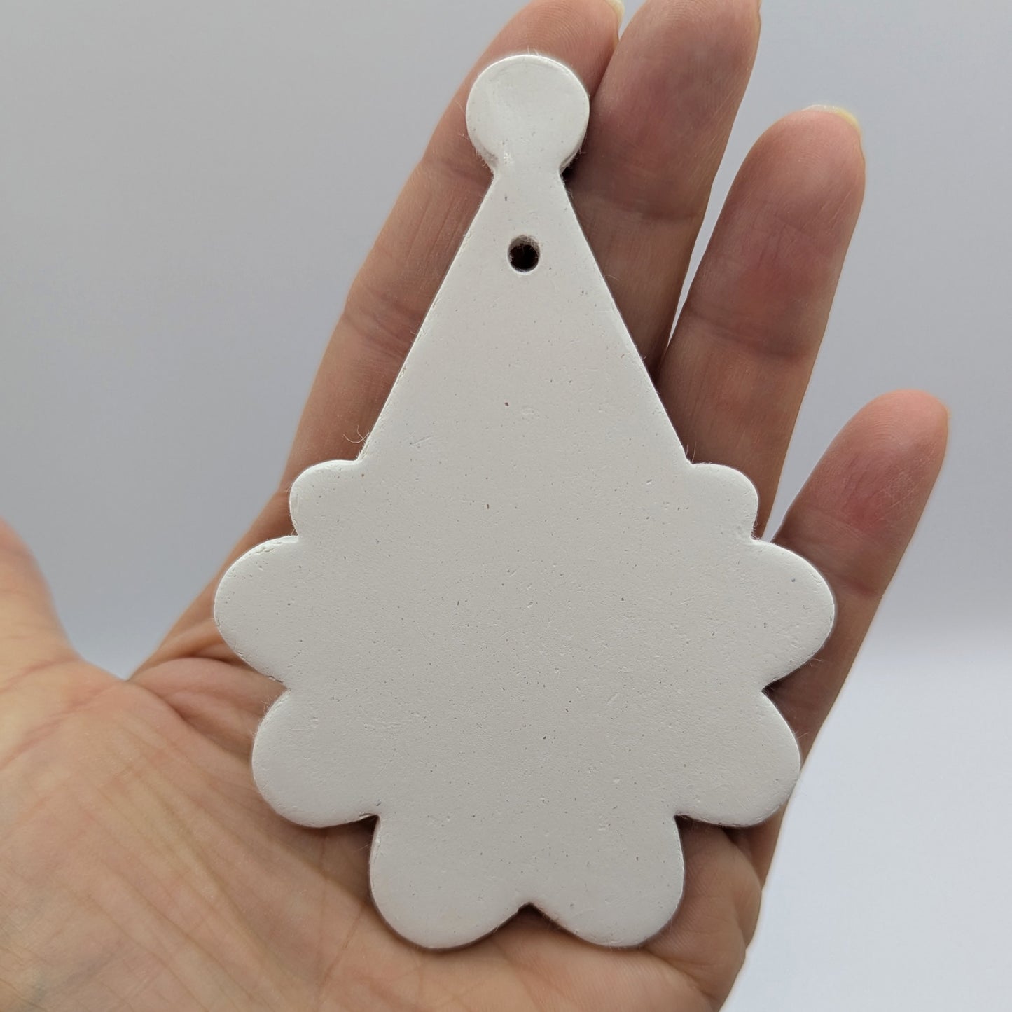 santa face and hat shaped clay decoration, held in the palm of hand