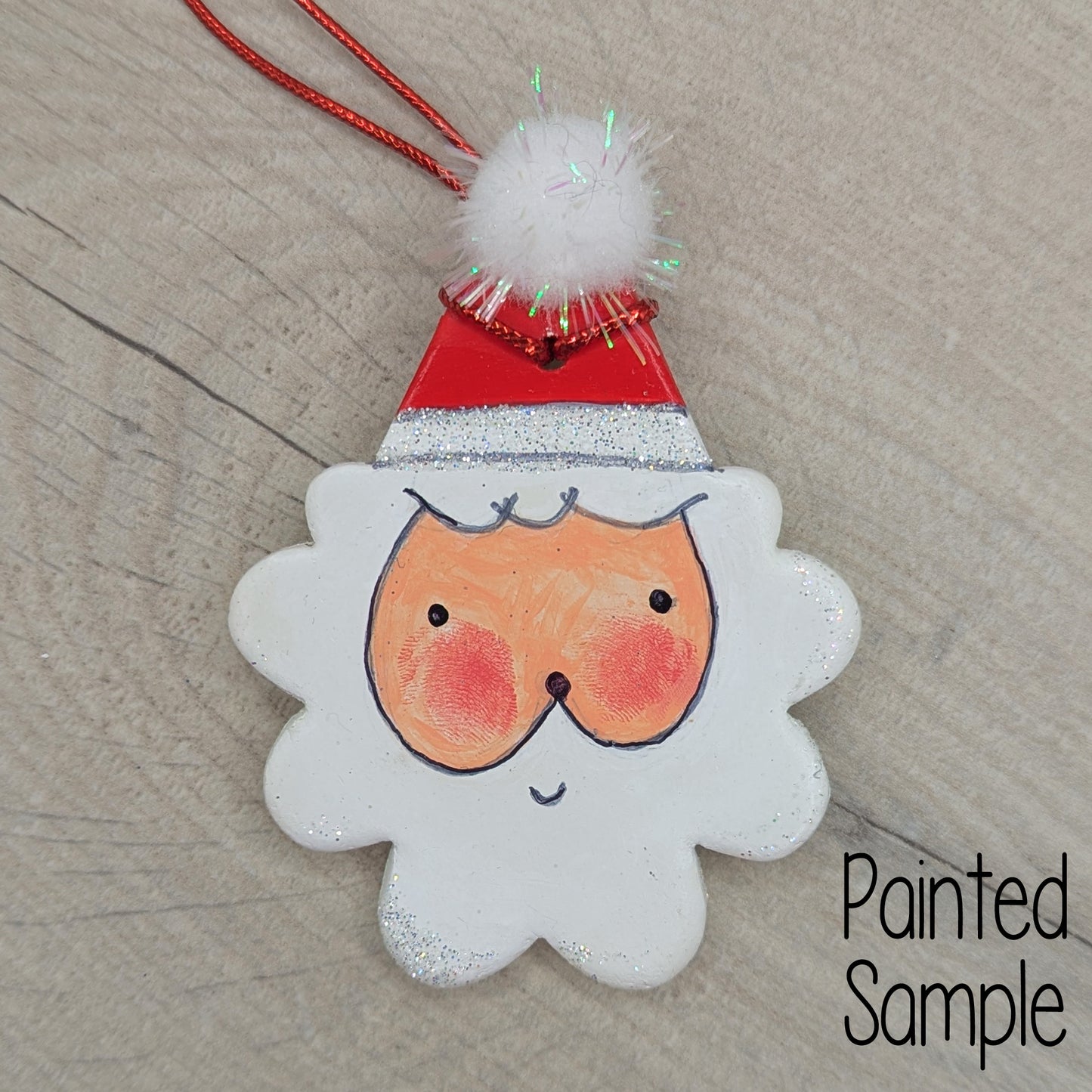 painted sample of santa clay decoration, painted in acrylic, with sharpie pen details, and a pom pom on top of his hat