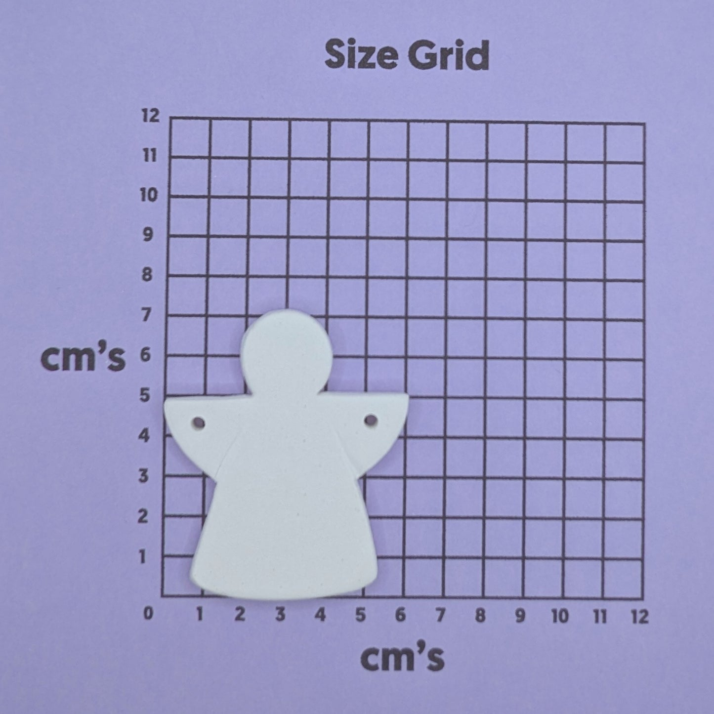 White angel decorationon a size grid with measurements in centimeters