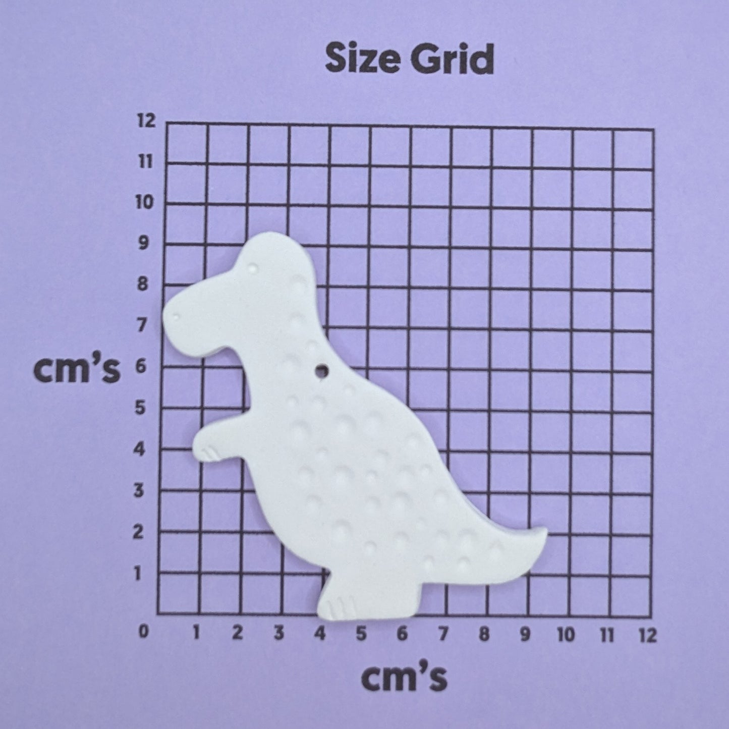 clay dinosaur decoration on a size grid with measurements in centimeters