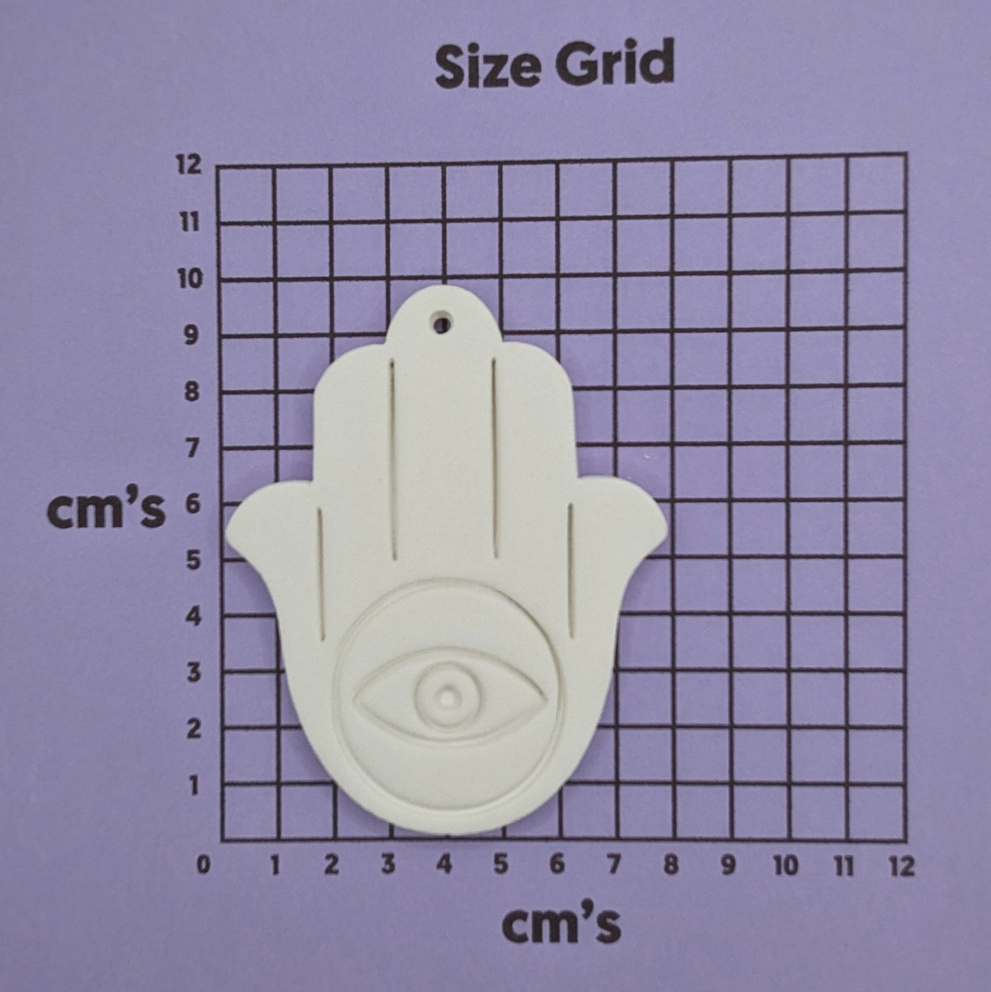 White Hamsa hand decoration on a size grid with centimeter measurements on a purple background