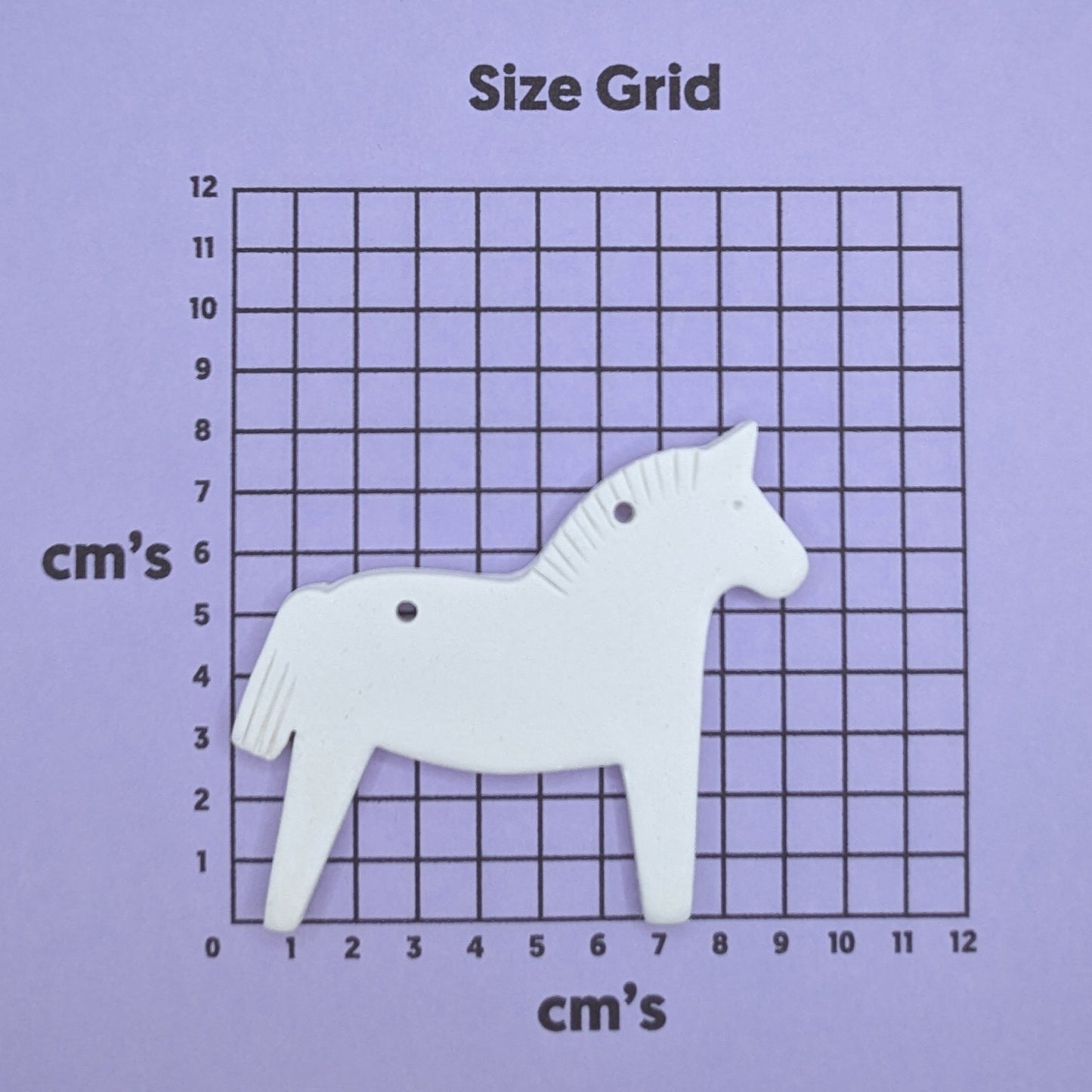 clay horse decoration on a size grid with measurements in centimeters