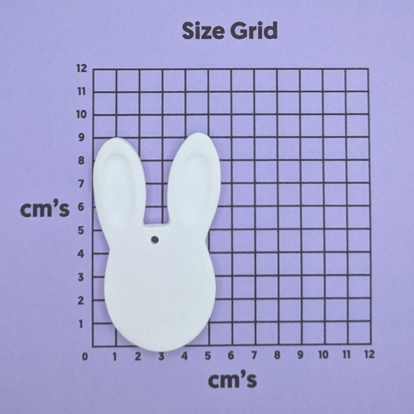clay rabbit face decoration on a size grid with measurements in centimeters