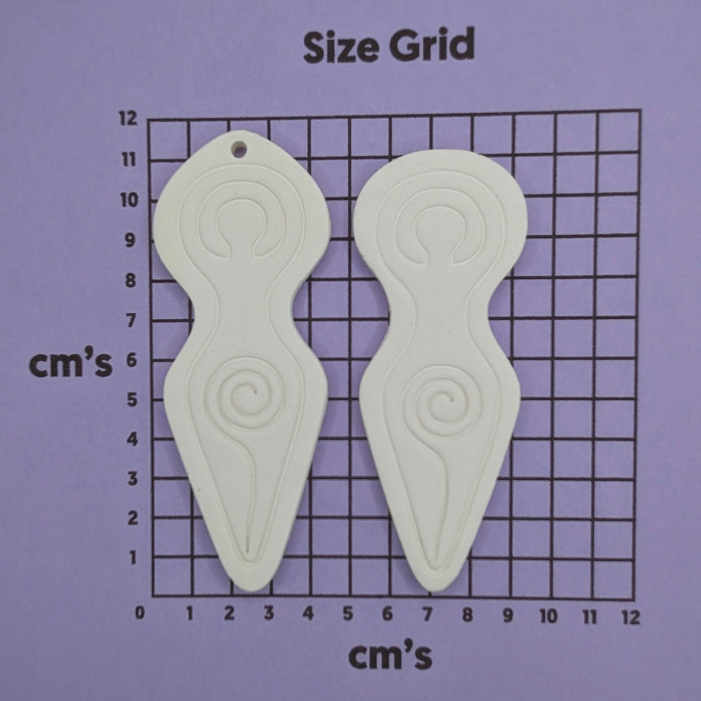 2 Spiral goddess shaped clay decoration shown on a cm size grid to show size