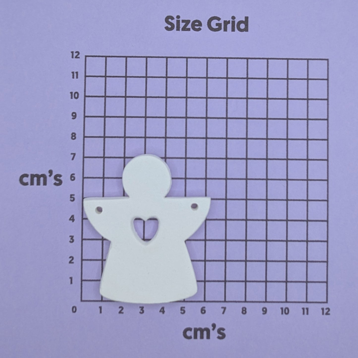 White angel-shaped decoration on a size grid with centimeter markings
