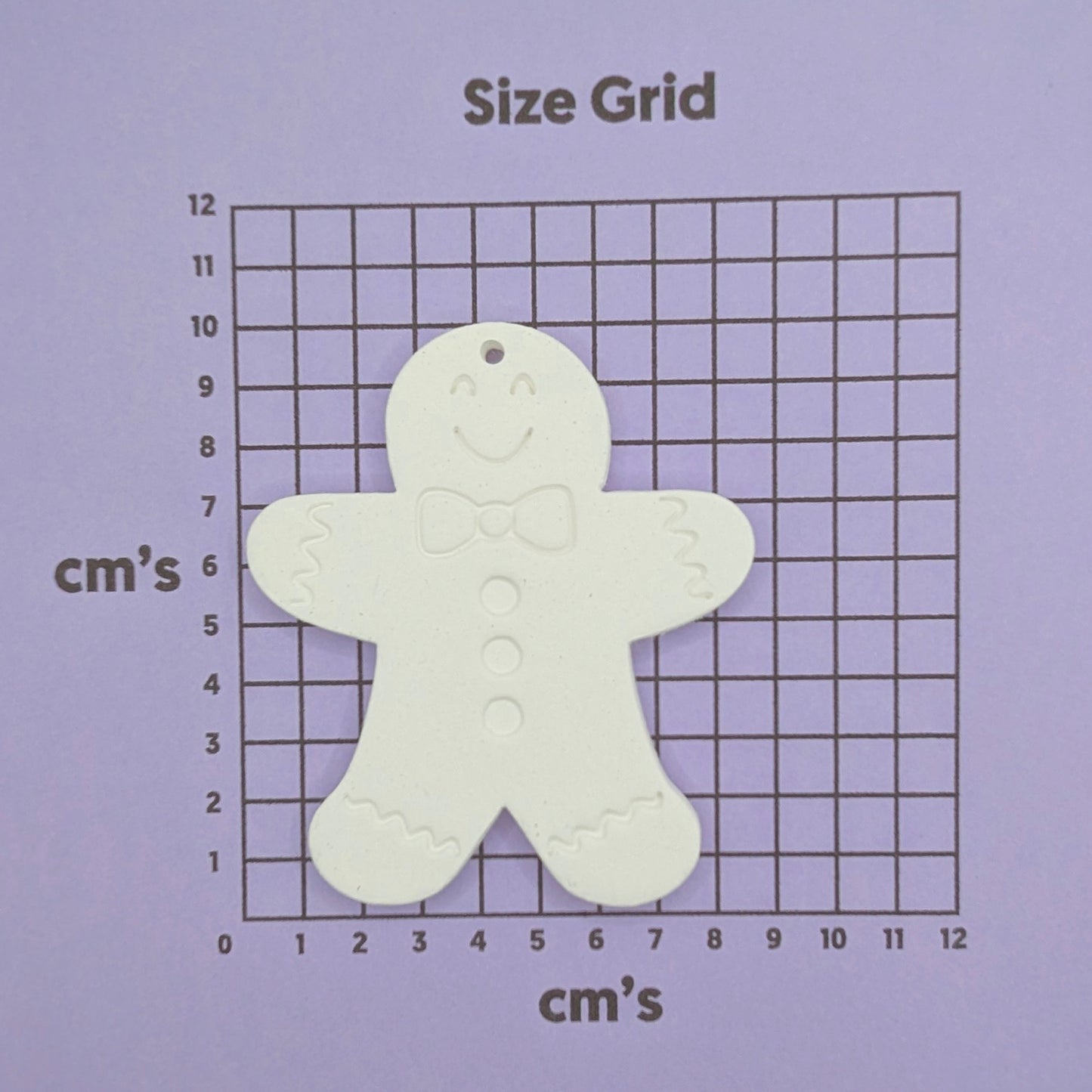 White clay gingerbread man on a purple size grid with measurements in centimeters.
