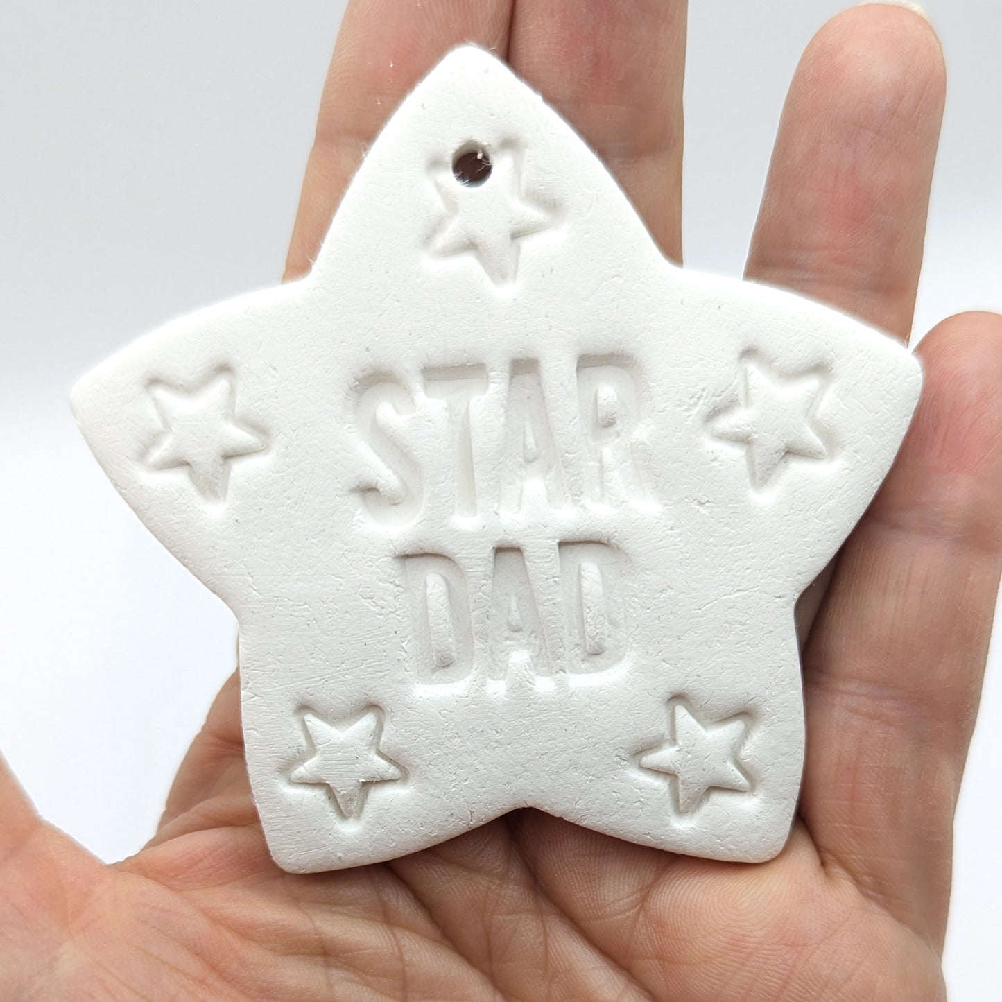 White star shaped clay decoration with 'Star Dad' and small stars stamped into it